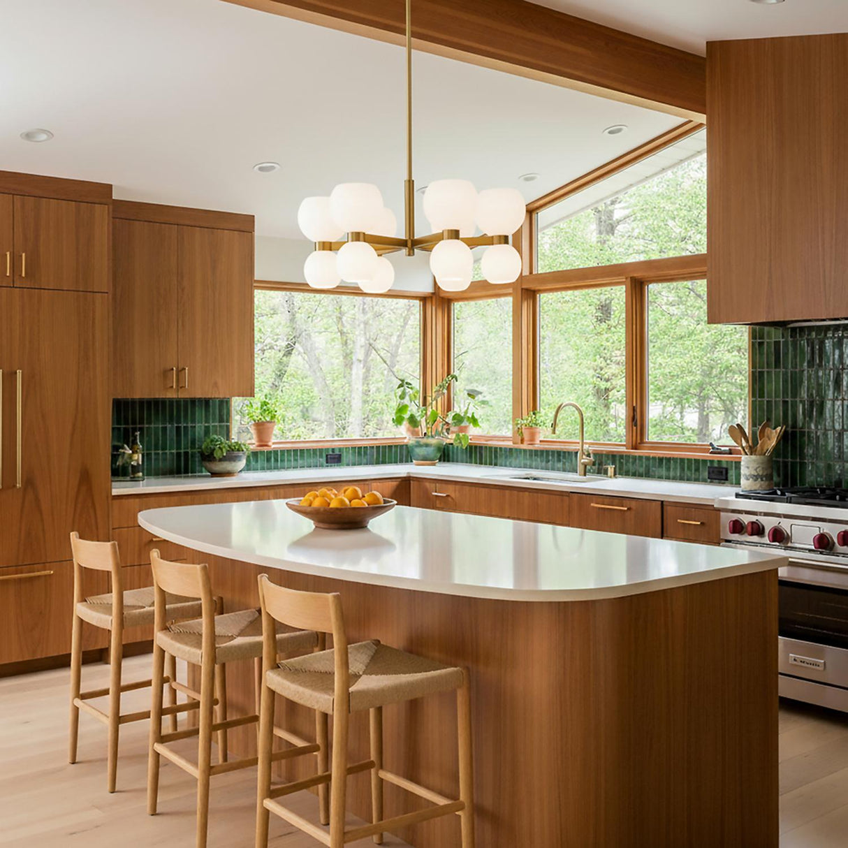 A mid-century kitchen featuring the Matilda Small Chandelier 28", Modern Brass and Milk Glass over a curved wood island with green tile backsplash and a beamed ceiling.