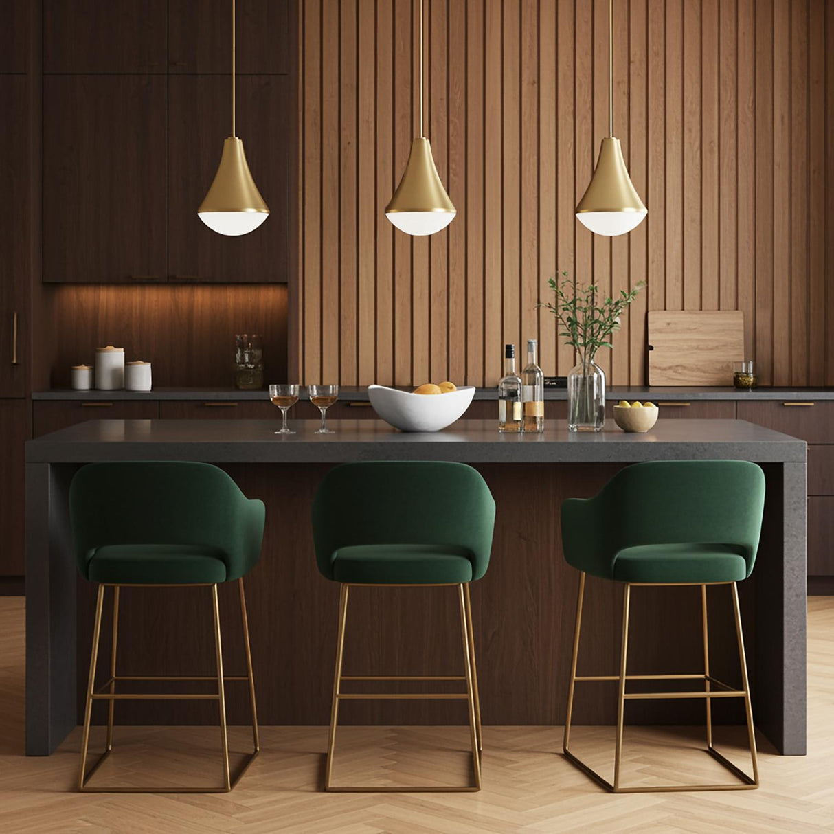 A modern kitchen featuring three Skylar Pendant 11 inch Satin Brass fixtures with frosted glass shades hanging over a dark gray island with green velvet stools.