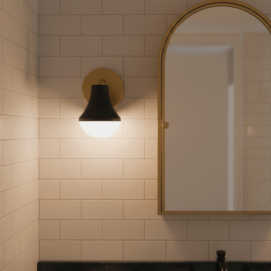 Skylar Wall Sconce 9, Matte Black and Satin Brass - Sconce mounted on a tiled wall next to a gold-framed mirror