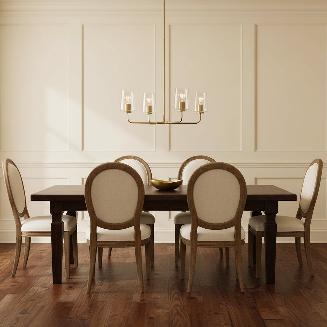 Wyatt 4 Light Chandelier 25 - A modern dining room with a brass chandelier over a dark wood table surrounded by upholstered chairs.