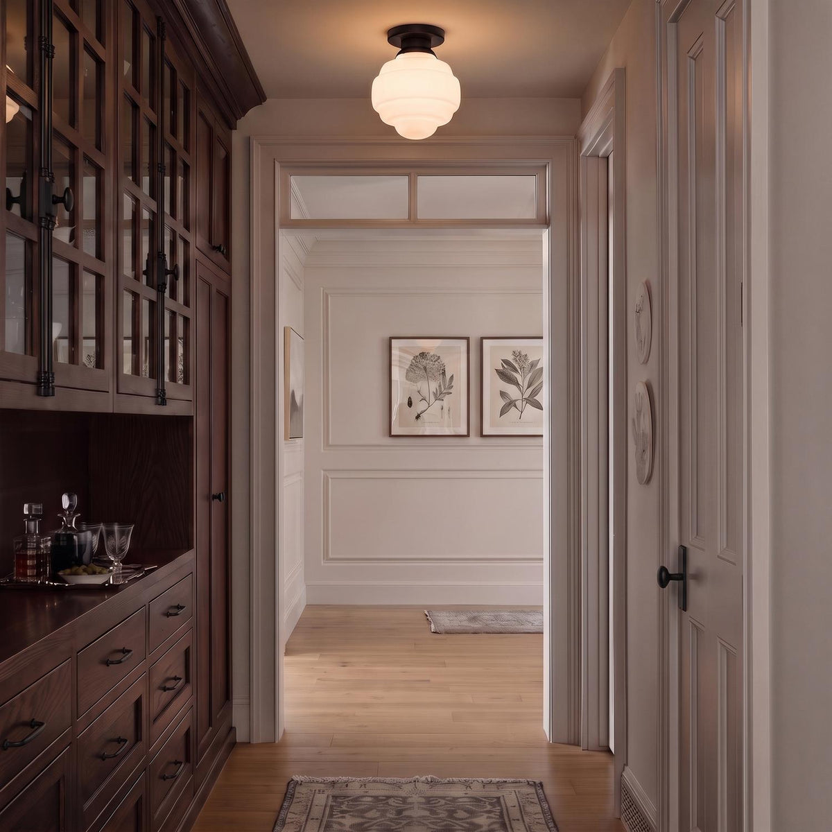 A transitional foyer features an Irving Medium Flush Mount 12", Black with a white glass shade set above dark wood cabinetry and light hardwood floors.