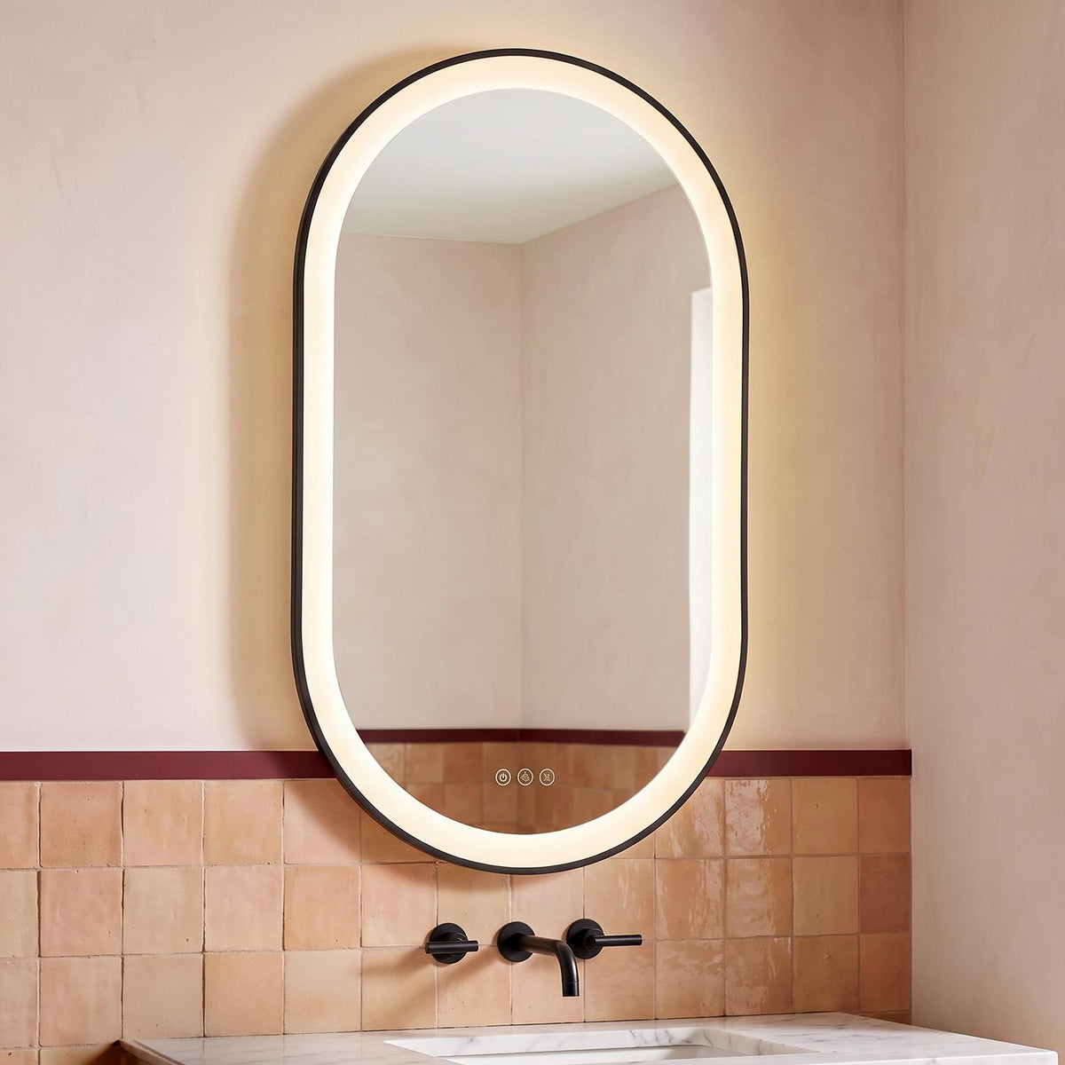 A contemporary bathroom with the Sherman Large LED Oval Mirror 24" x 42", Brushed Black mounted above a white marble vanity and matte black faucet against terracotta tiles.