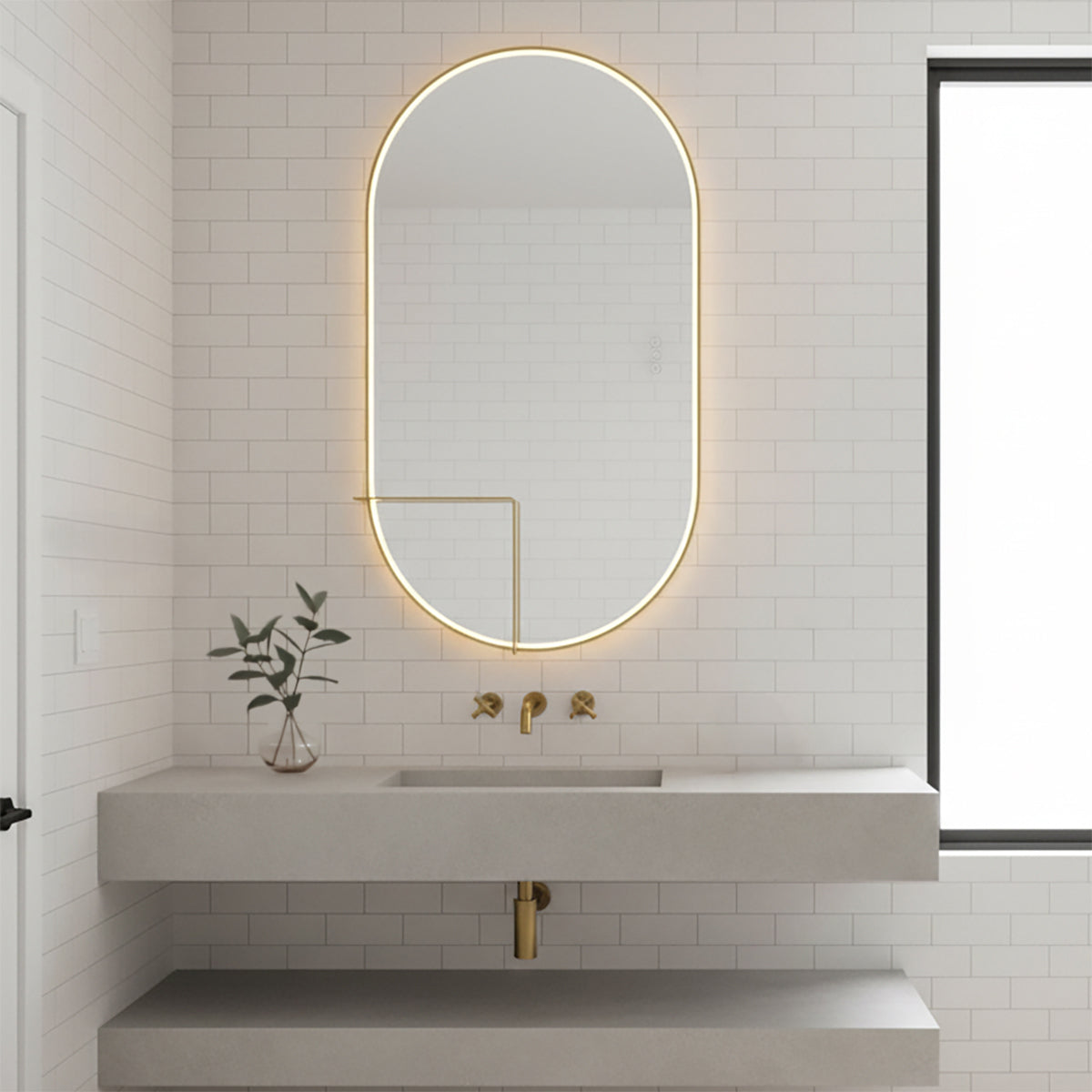 Chadwick Large LED Oval Mirror 24" x 42", Brushed Brass - An oval LED mirror in a bathroom setting with a floating vanity and white subway tile.