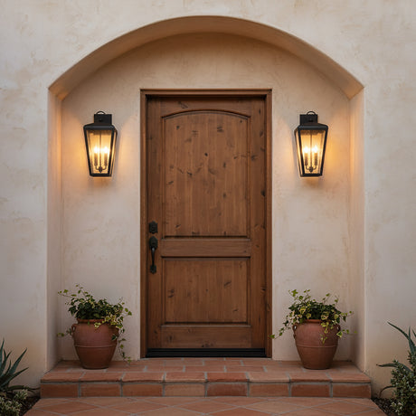 Barrett Outdoor Wall Light, Medium 20" Textured Black - Two black lanterns flanking a rustic wooden door with an arched stucco entryway