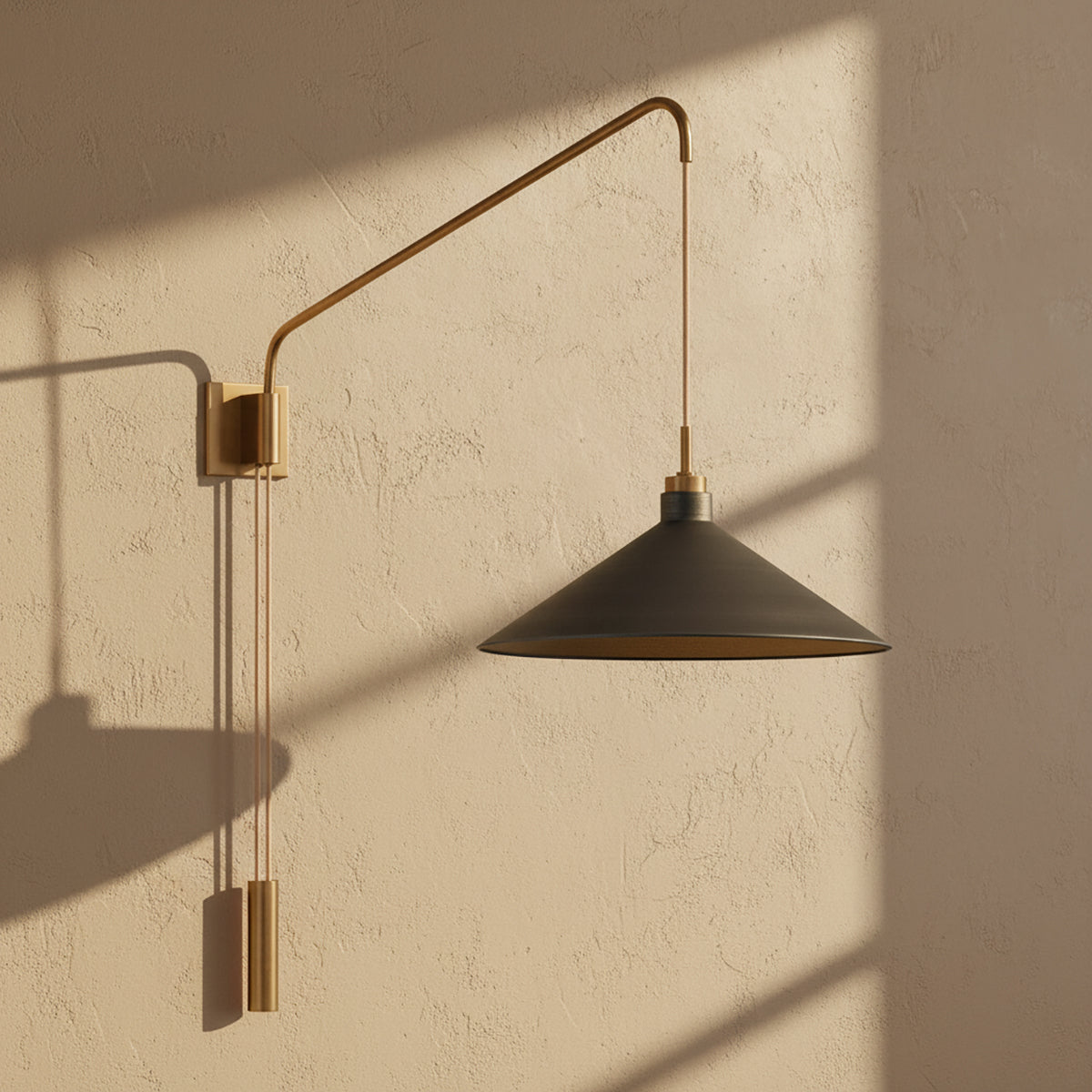 Gideon Wall Sconce - A graphite and patina brass wall sconce against a textured wall with dappled sunlight shadows.