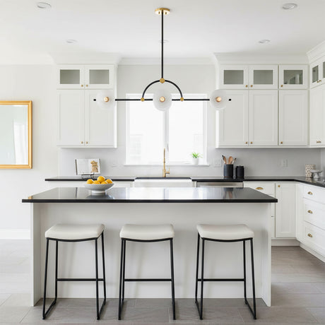 Penrose 6 Light Linear Pendant 43, Aged Brass and Textured Black - A modern kitchen island with white stools and a contemporary pendant light.