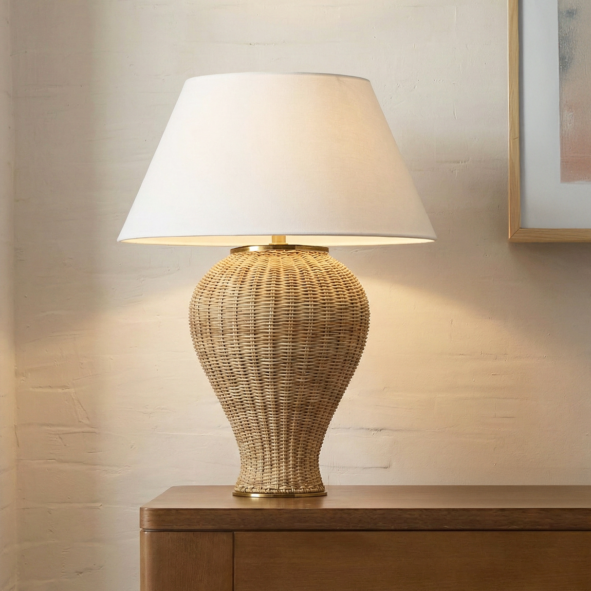 Wicker table lamp is 30" tall with white shade on a wooden console table against a neutral wall.