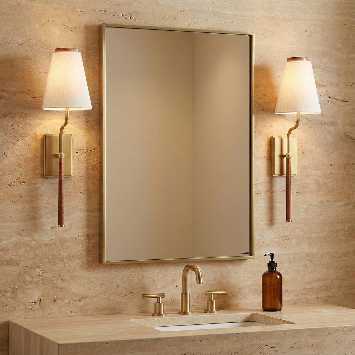 Brushed Brass and brown woven wall sconce in a Transitional Bathroom with a travertine vanity and gold mirror.