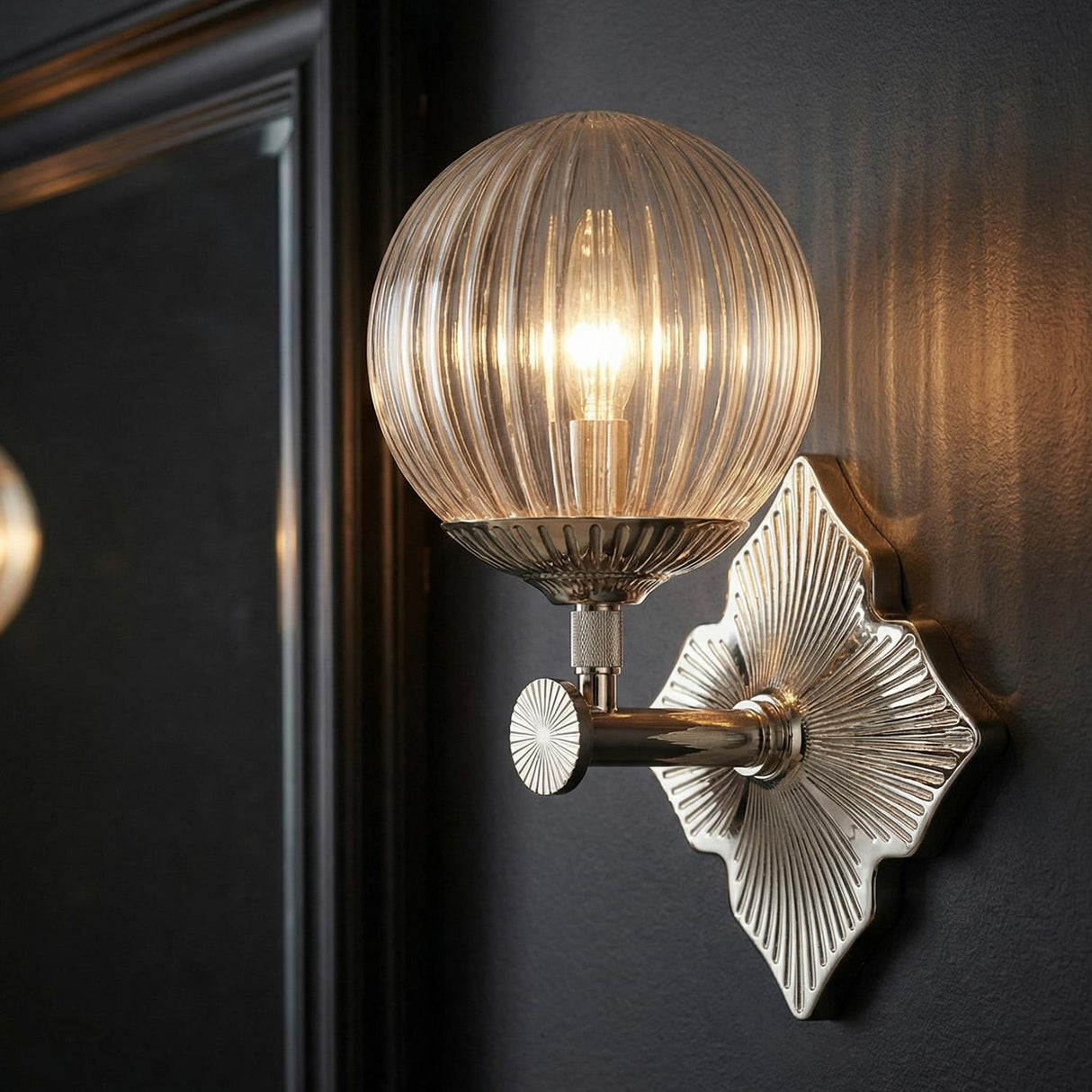 Victoria Wall Sconce 12", Polished Nickel and Clear Ribbed Glass globe Wall Sconce in a Contemporary Bathroom with a black framed mirror.