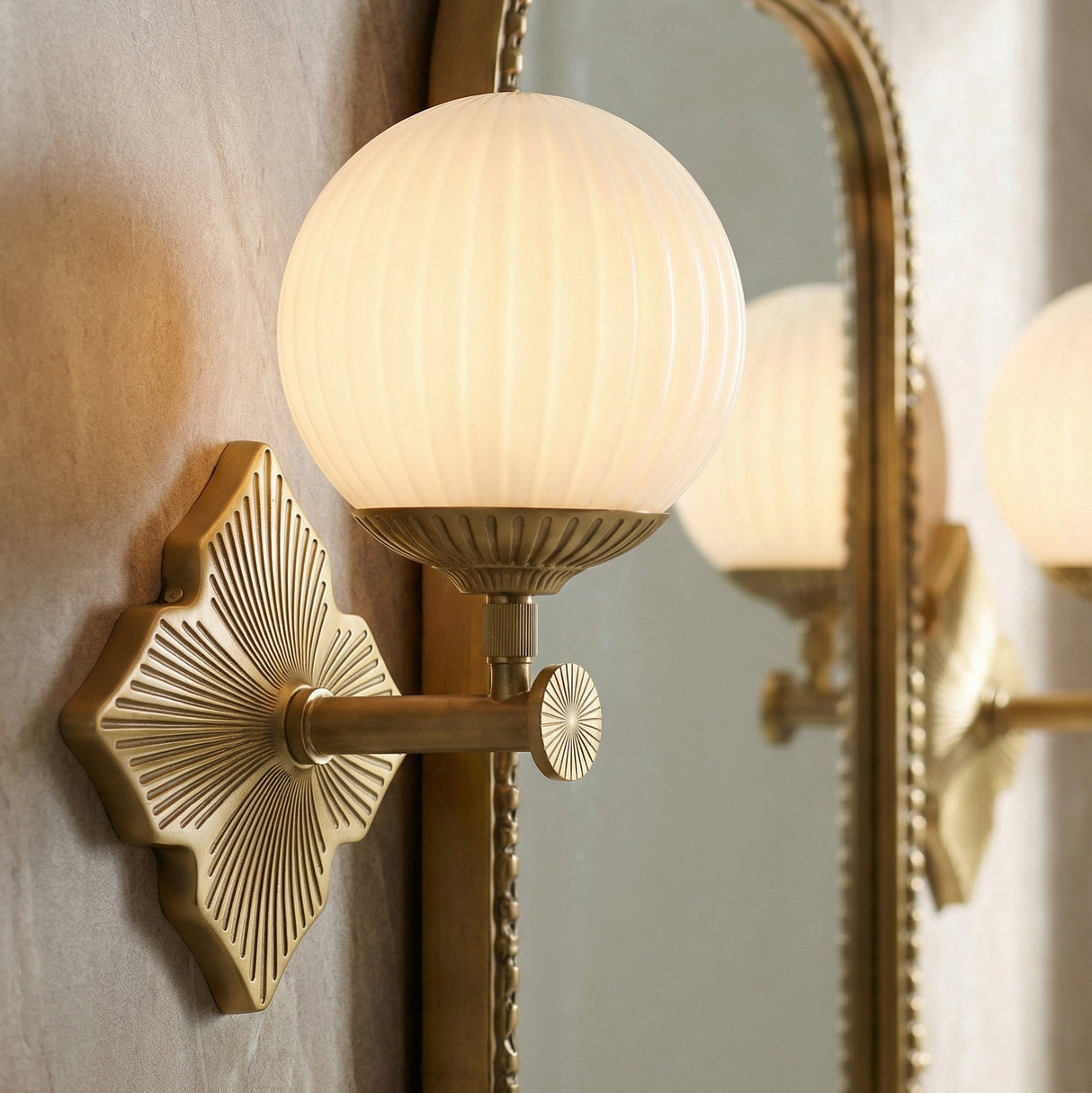 Victoria Wall Sconce 12", Aged Brass and Opal Ribbed Glass globe wall sconce in a Contemporary Bathroom with an arched brass mirror.