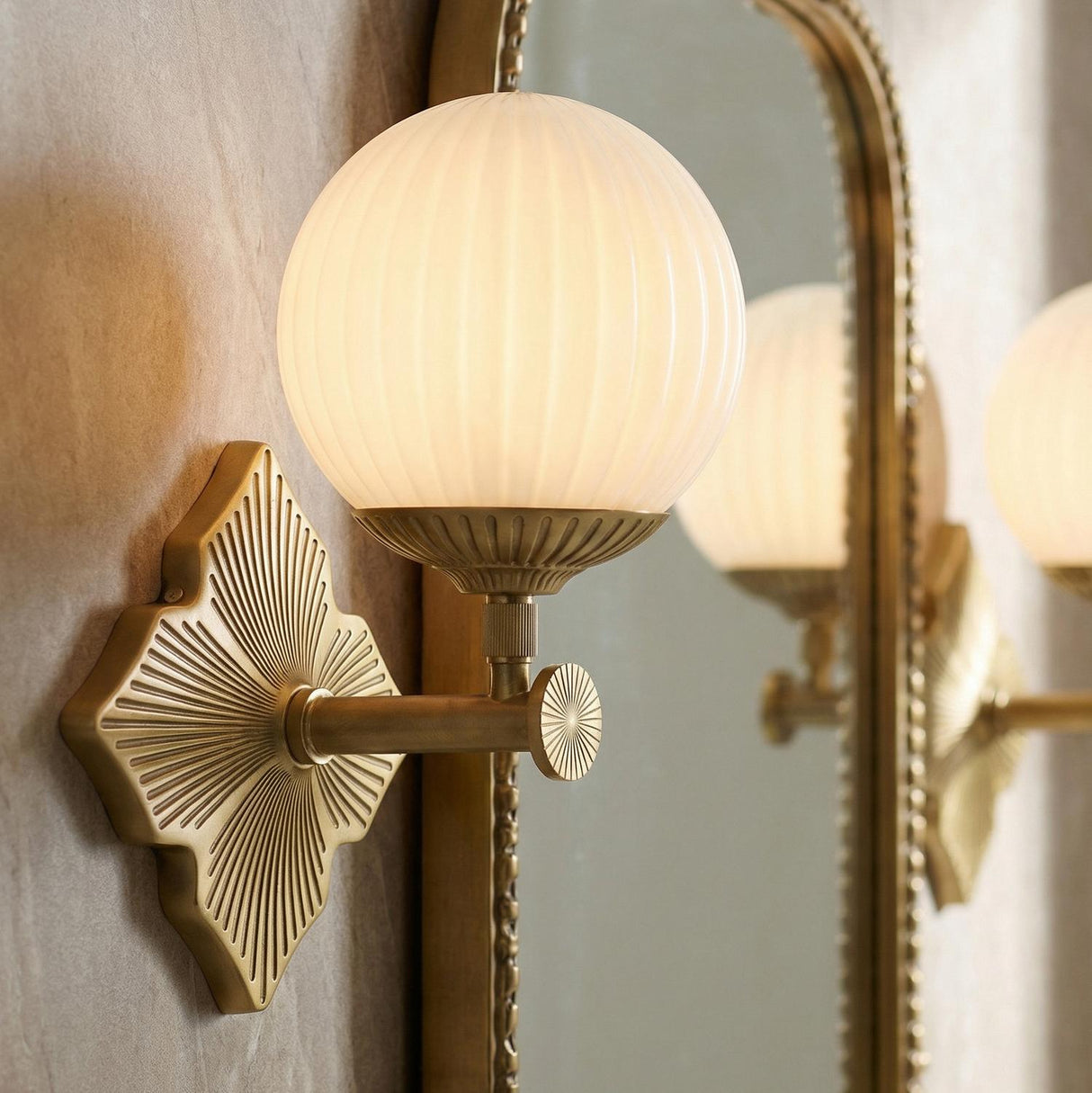 Victoria Wall Sconce 12", Aged Brass and Opal Ribbed Glass globe wall sconce in a Contemporary Bathroom with an arched brass mirror.