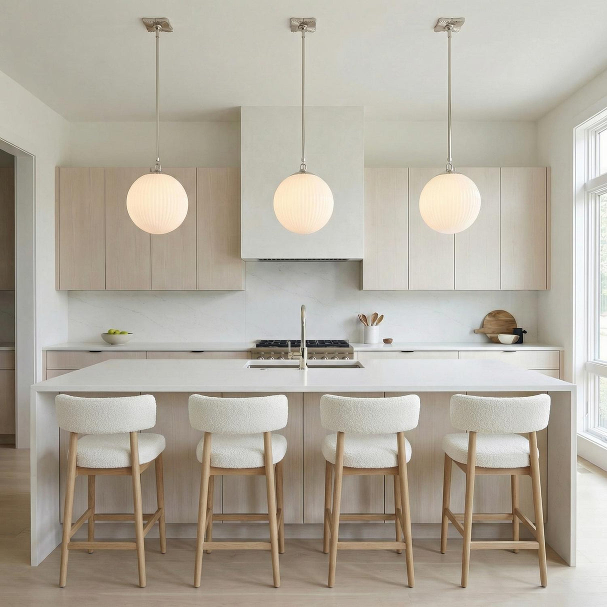 Victoria Pendant, Polished Nickel and Opal Ribbed Glass globe pendant in a Modern Kitchen with a white island and bouclé stools.