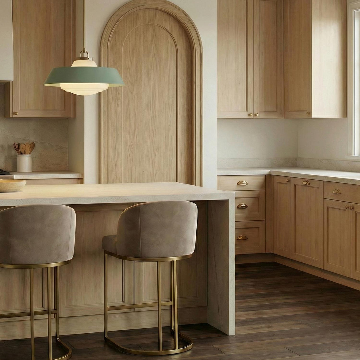 A modern kitchen featuring the Blaine Large Pendant 20", Brass and Sage Green with frosted glass over the island, flanked by natural wood cabinetry and an arched door.