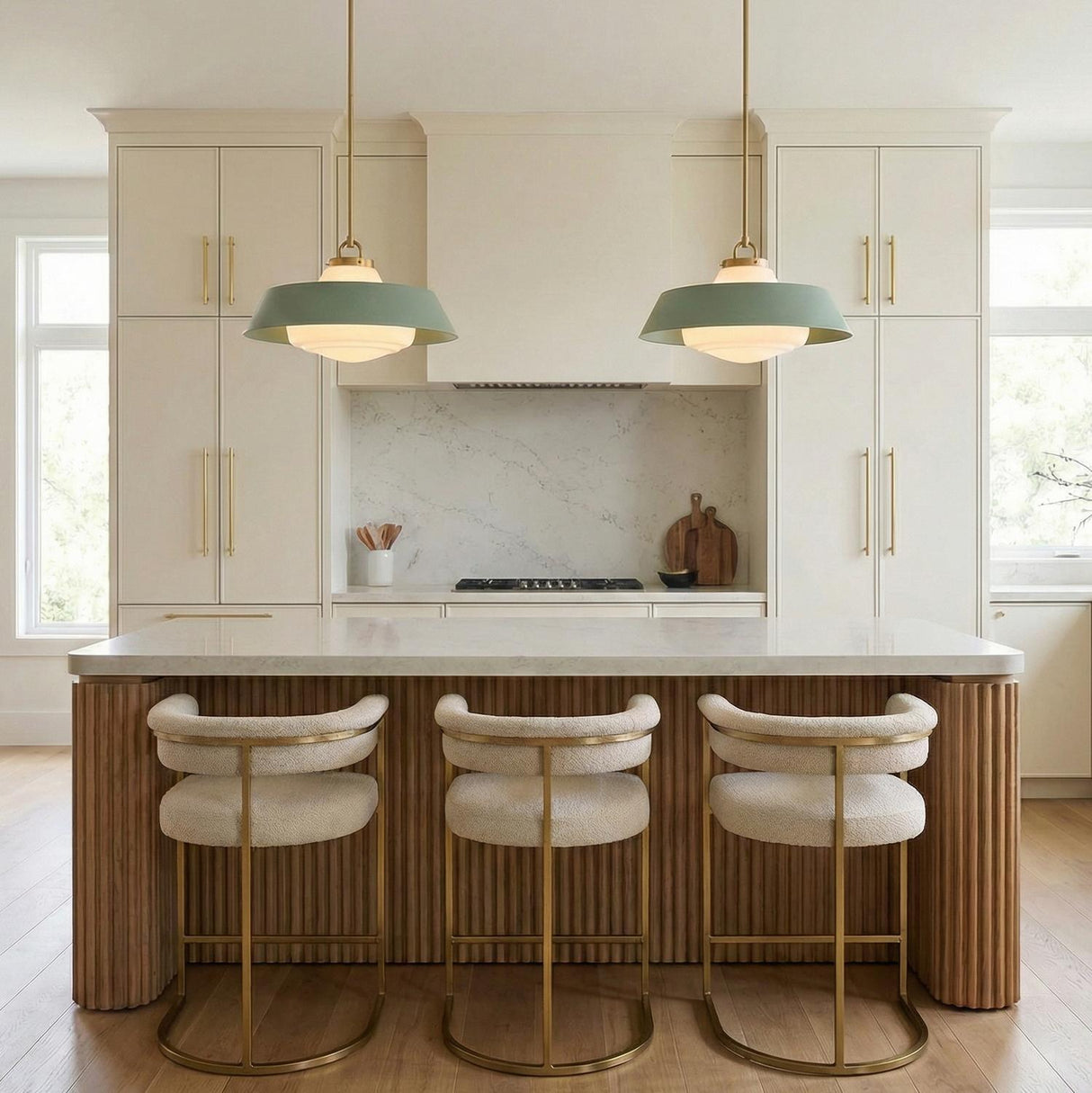 A contemporary kitchen features two Blaine Large Pendant 20", Brass and Sage Green with brushed brass hardware over a fluted wood island and marble backsplash.