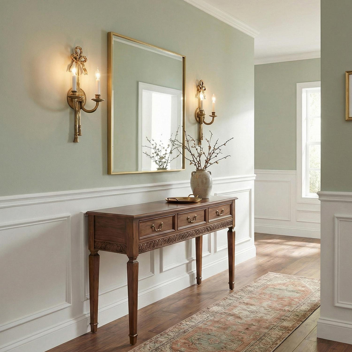 Bow Ribbon Antique Brass ribbon design Wall Sconce in a Traditional Entryway with a wooden console table and gold mirror.