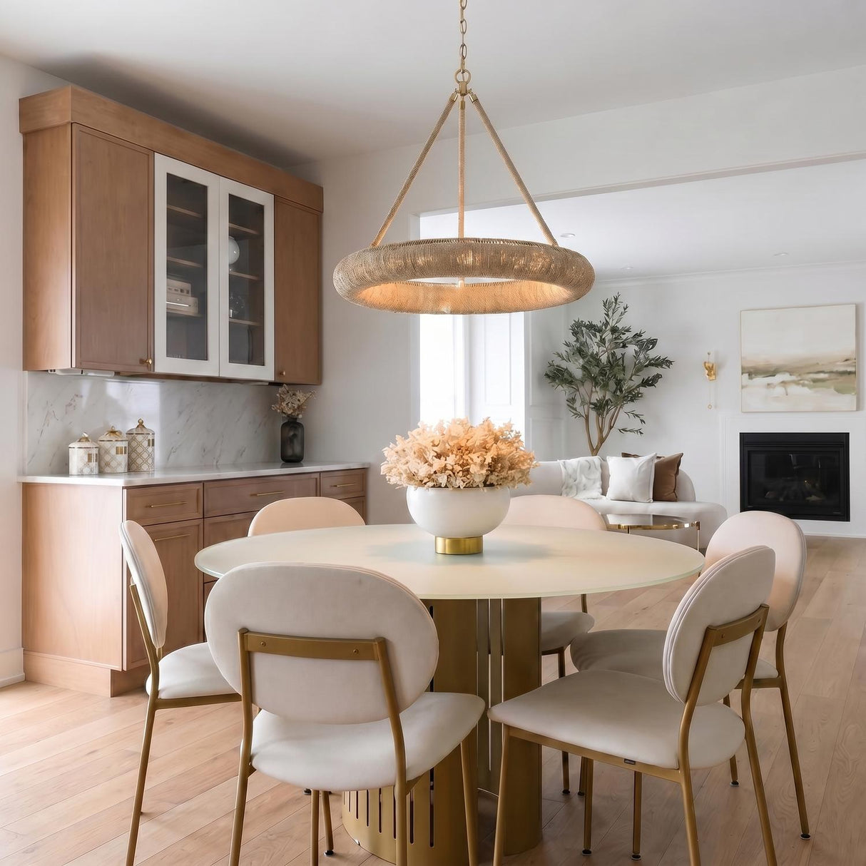 A contemporary dining room featuring the Seabrook LED Chandelier in lake grass and soft brass over a round cream table and chairs with brass legs.