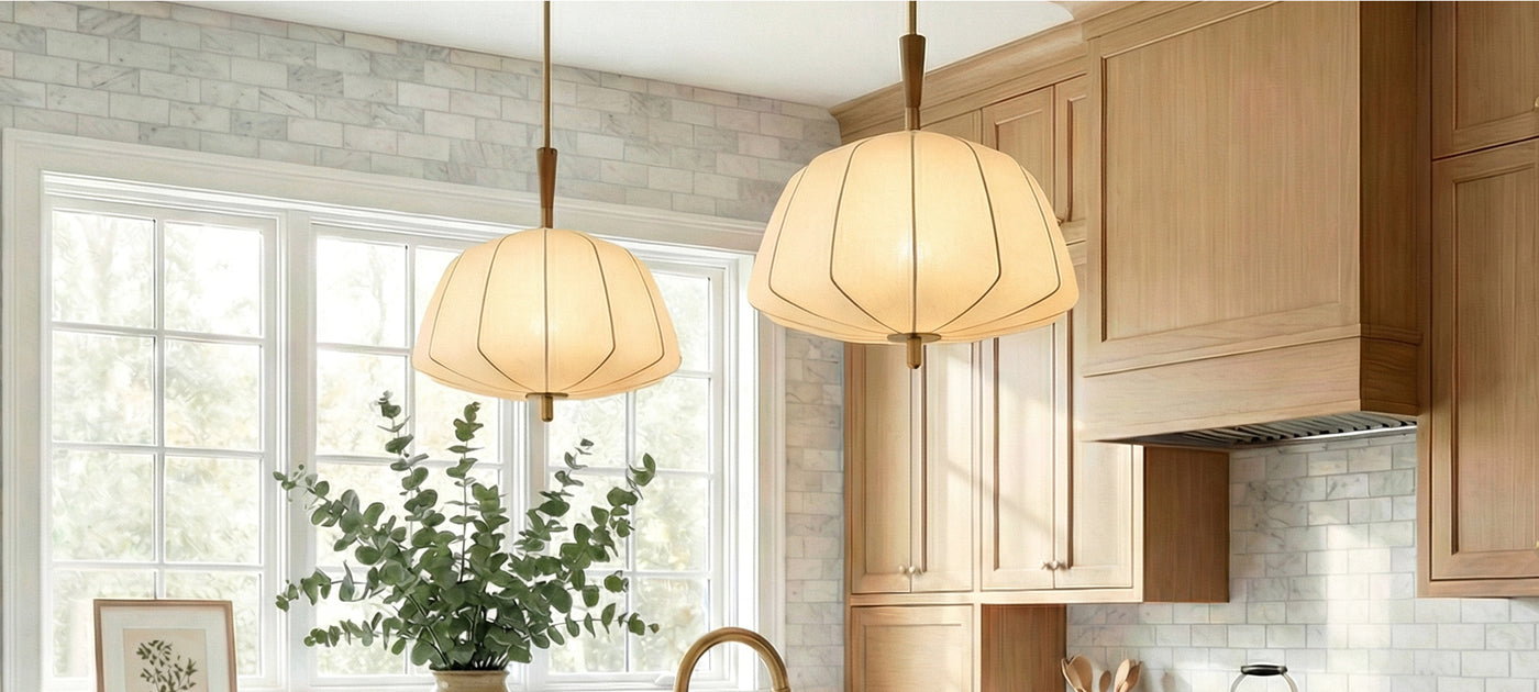 Two Winthrop Fabric stretched pendants with wood details in a modern kitchen with wooden cabinets, marble subway tiles, and a plant.