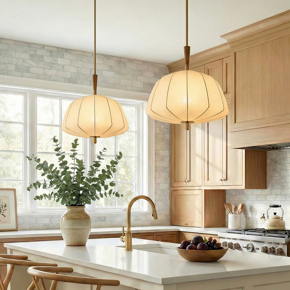 Two Winthrop Fabric stretched pendants with wood details in a modern kitchen with wooden cabinets, marble subway tiles, and a plant.