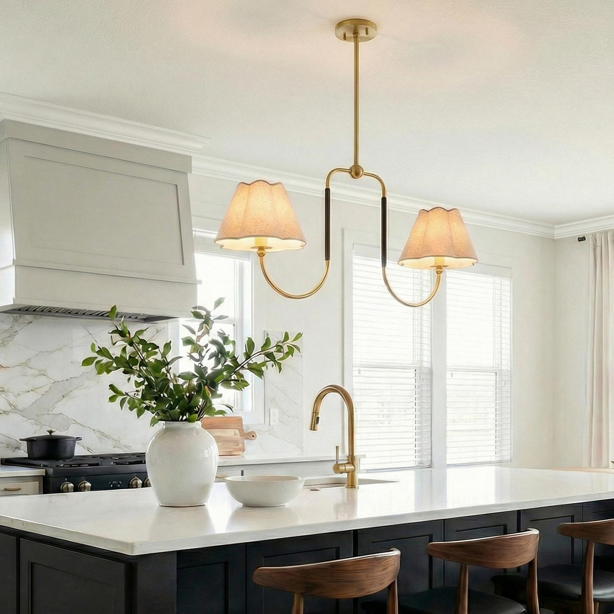 A transitional kitchen features the Sara 2 Light Linear Pendant 42", Aged Brass and Bronze over the white marble island with dark cabinets and a marble backsplash.