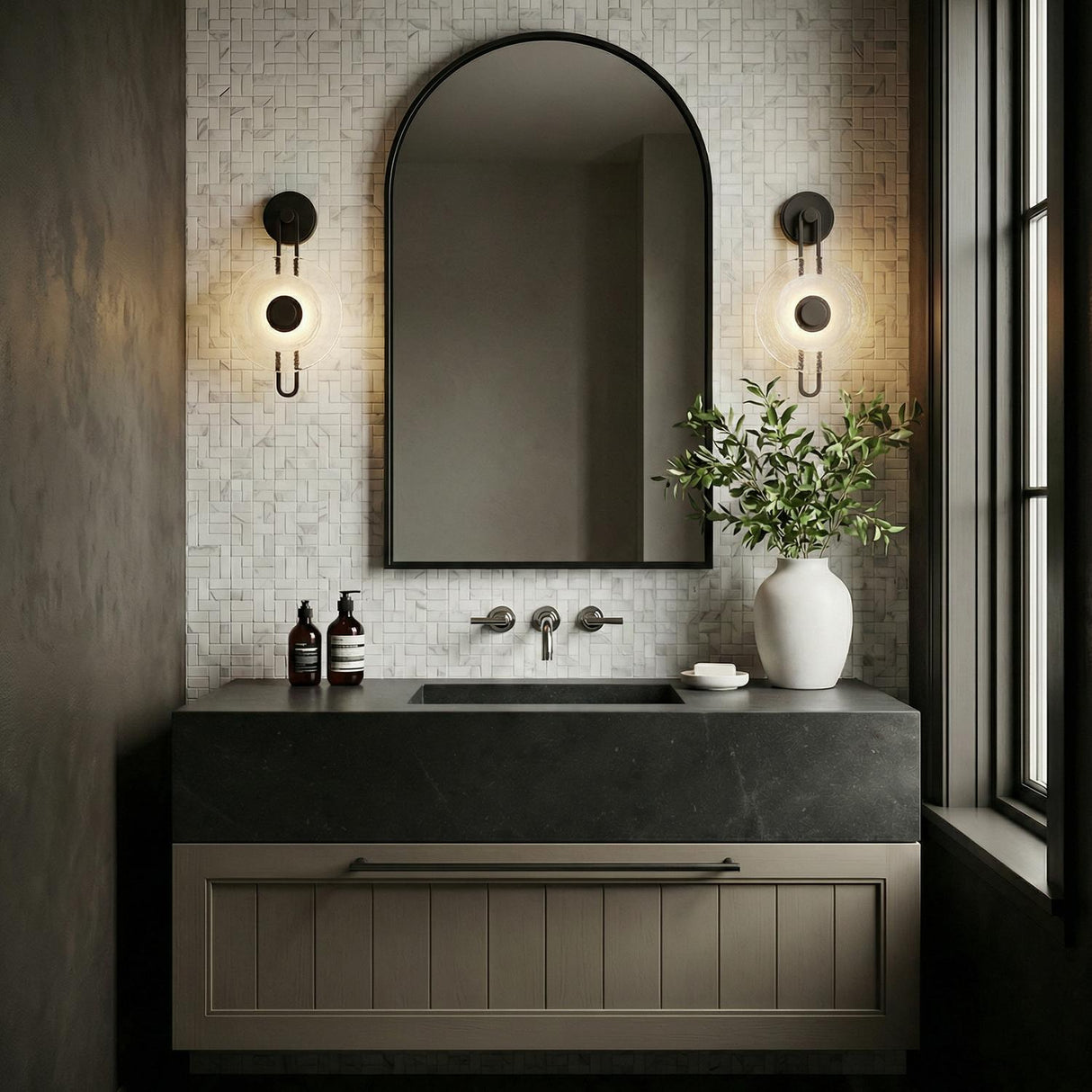 Quella LED Wall Sconce 18", Old Bronze and Piastre Glass geometric wall sconce in a Modern Bathroom with an arched mirror and stone vanity.