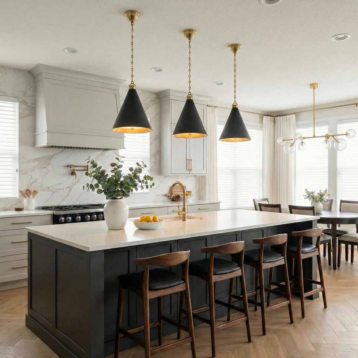 A transitional kitchen with three Ambrose Medium Pendant 15" Urban Bronze and Aged Brass fixtures hanging over a dark gray island with white marble countertops and walnut barstools.
