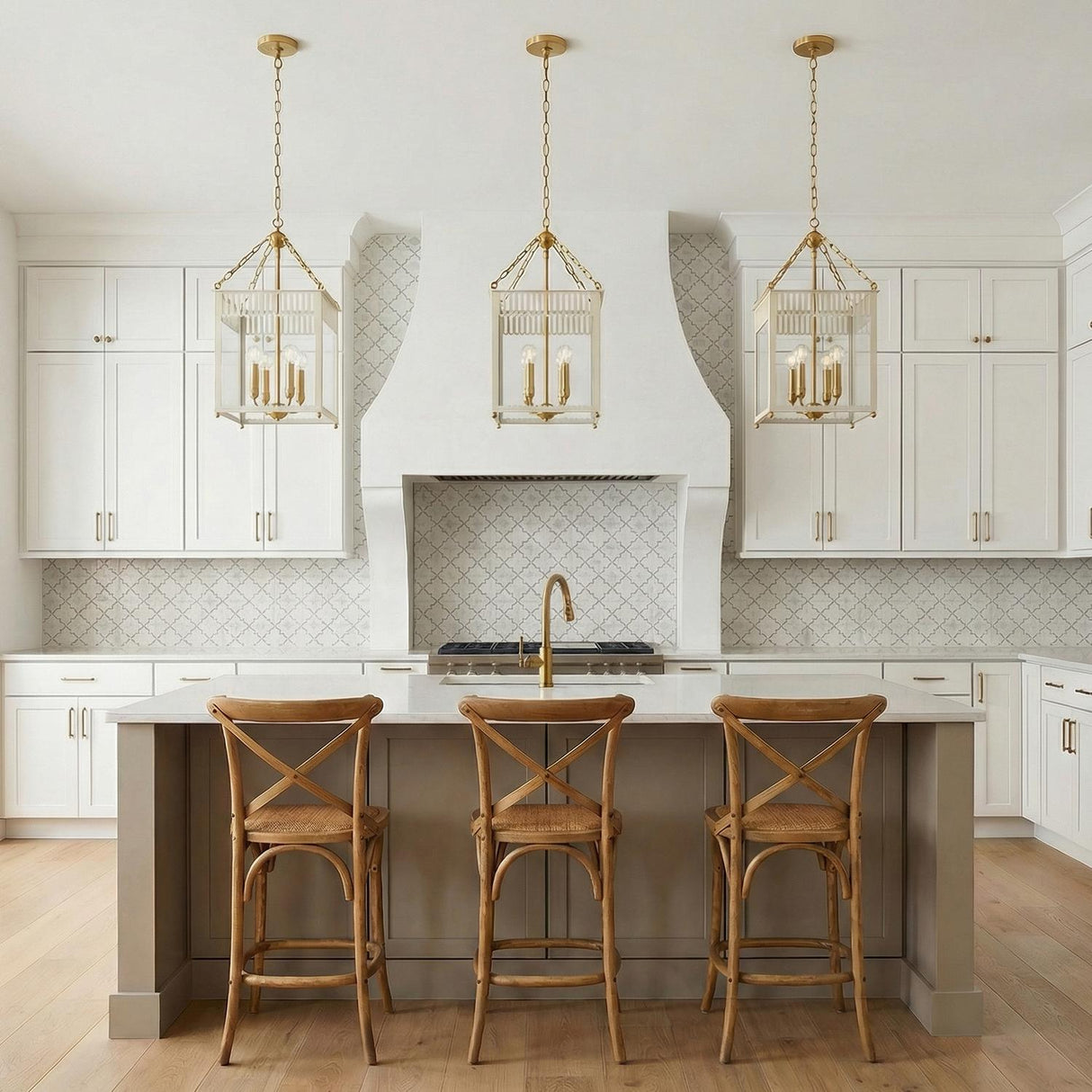 A transitional kitchen featuring three Roanne Medium Lantern Pendant 13-inch, Cream and Aged Brass fixtures over the island with white cabinets and a patterned tile backsplash.