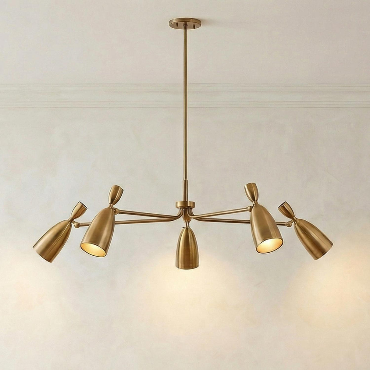 Hyla 5 Light Chandelier 50", Patina Brass geometric Chandelier in a Mid-Century Dining Room with a textured plaster wall.
