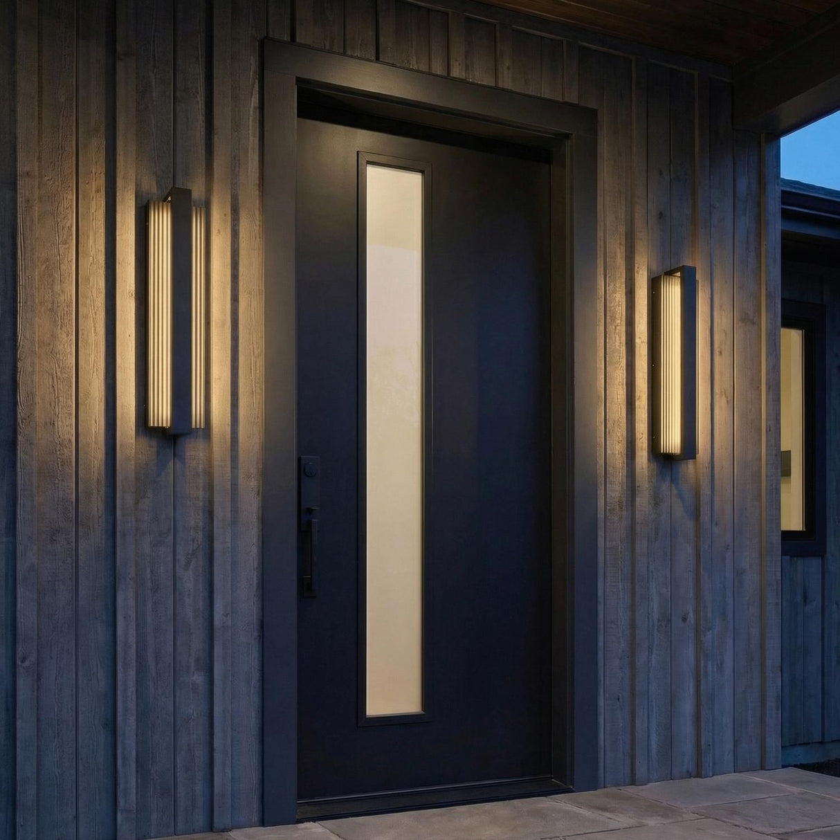 Zenith Matte Black 24" linear Outdoor Wall light in a Modern Outdoor entryway with dark wood siding and a black front door.