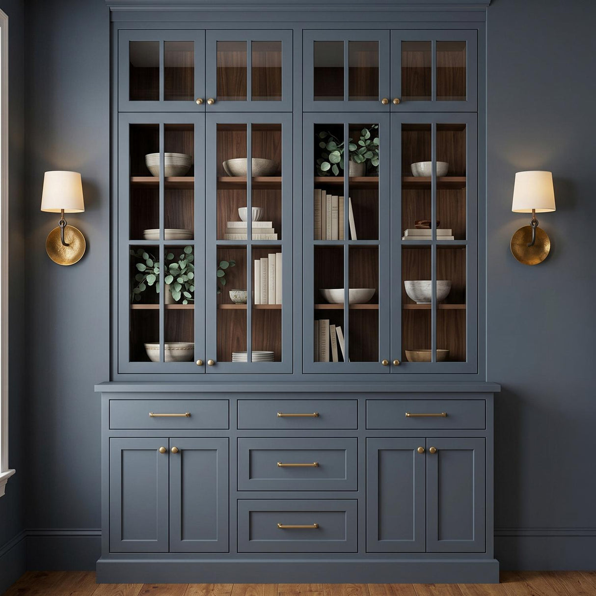 A transitional dining room with two Galen Wall Sconce 16", Hammered Antique Brass wall sconces flanking a slate blue built-in cabinet featuring glass doors and walnut shelves.