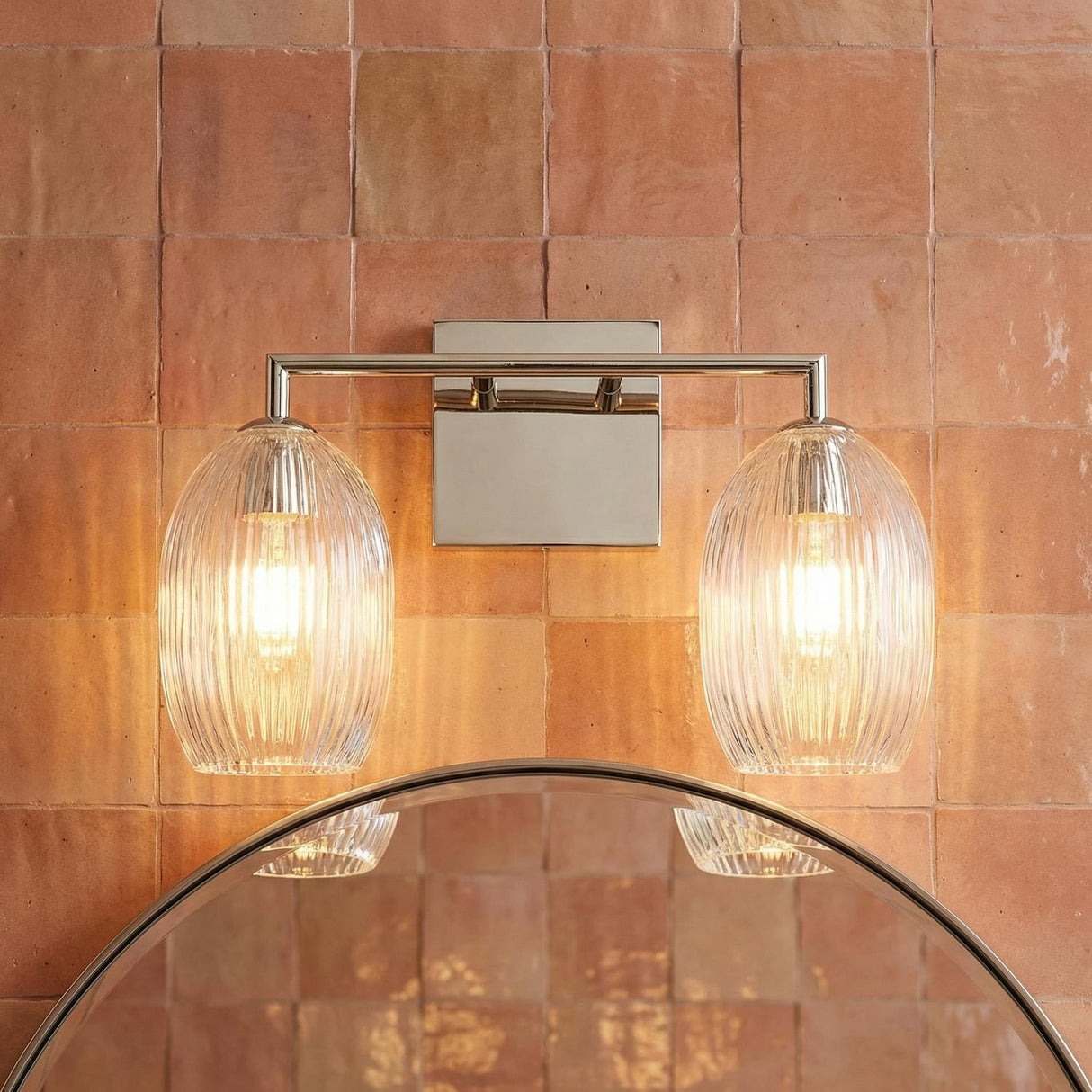 Fiora 2 Light Vanity 16", Polished Nickel ribbed glass Vanity in a Mediterranean Bathroom with terracotta tiles and a round mirror.