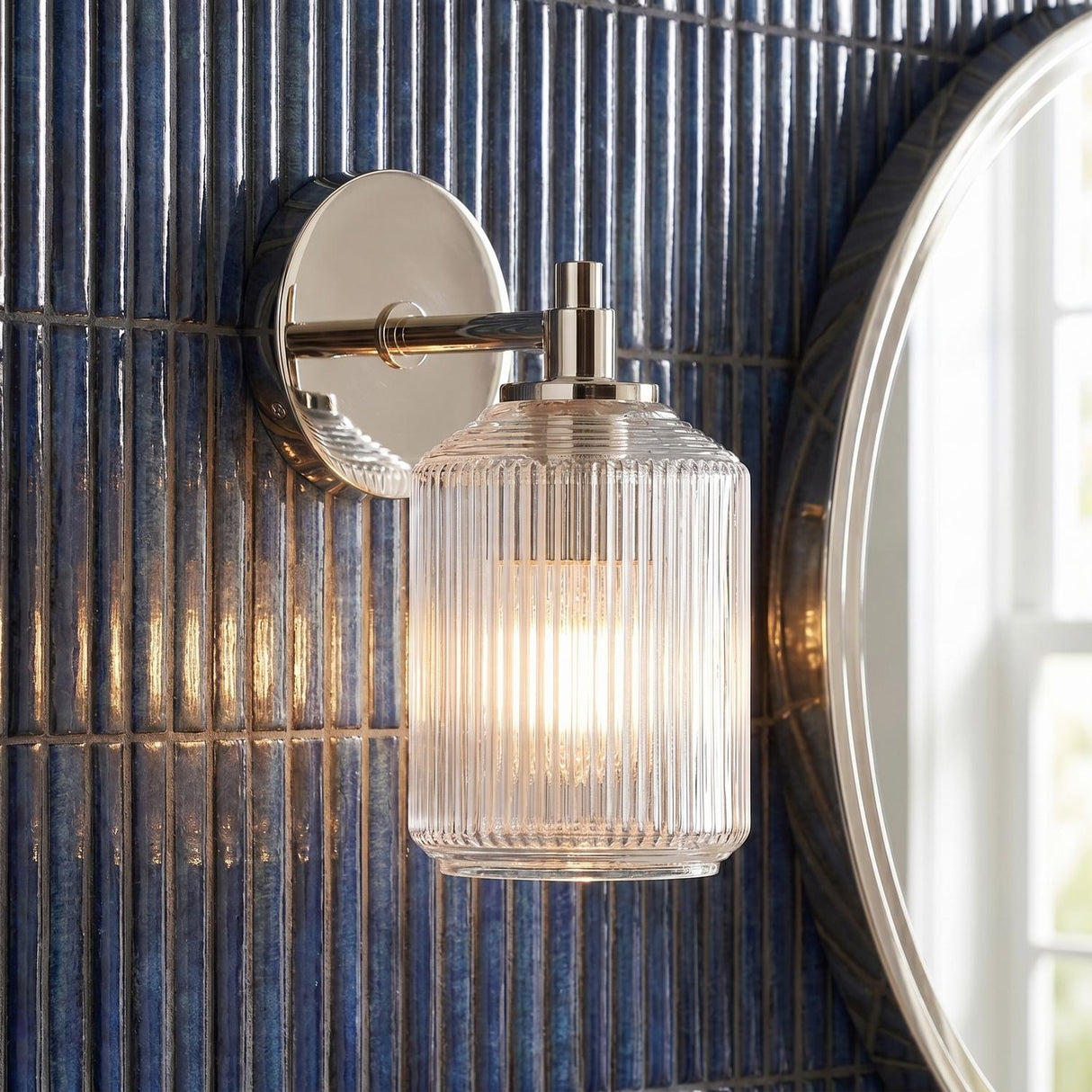 Lathan Wall Sconce 9", Polished Nickel linear Wall Sconce in a Contemporary Bathroom with blue vertical tile and a round mirror.