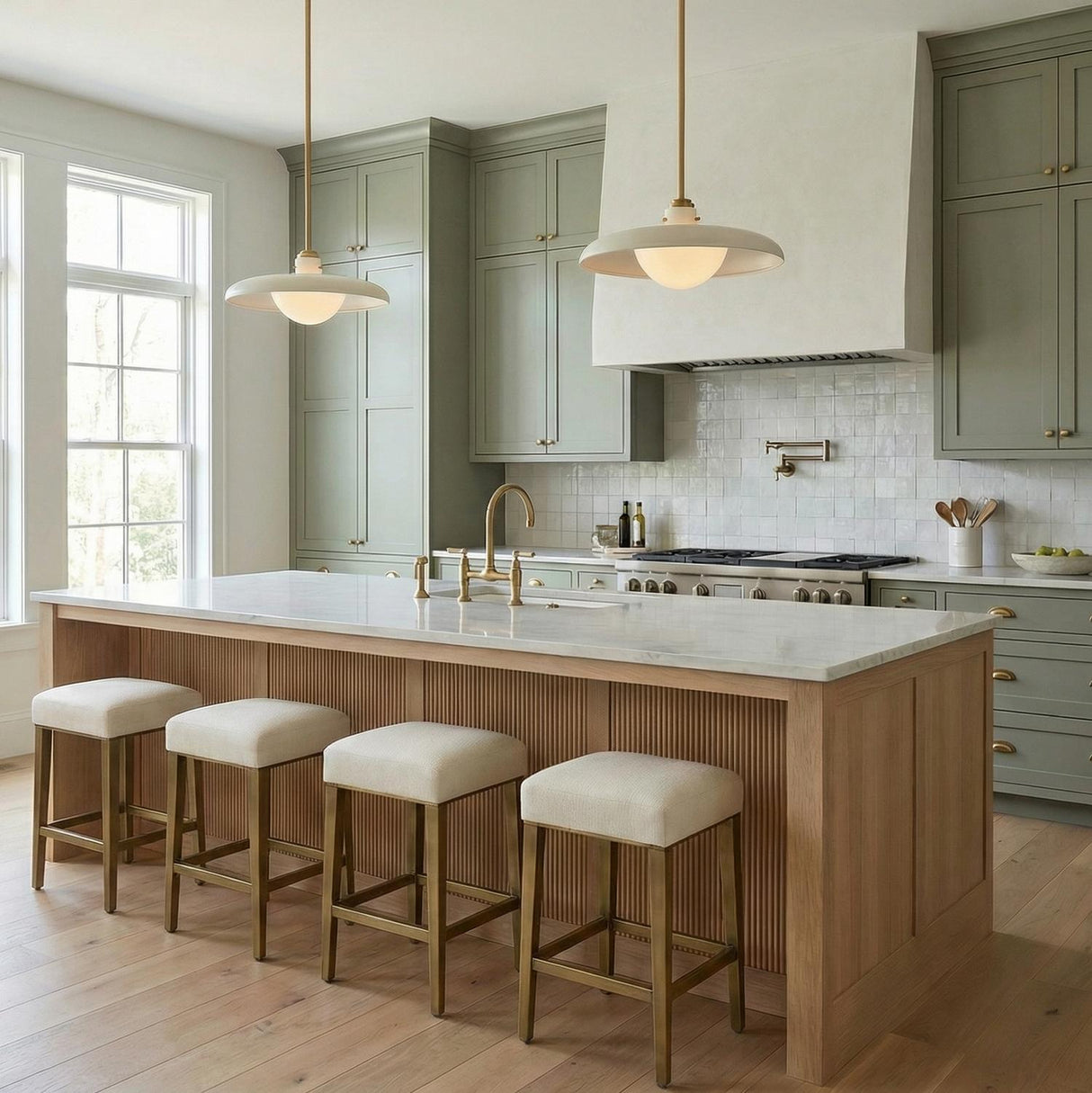 A transitional kitchen with two Bain Large Pendant 20", Off-White and Patina Brass fixtures over a marble island featuring sage green cabinetry and a fluted wood base.