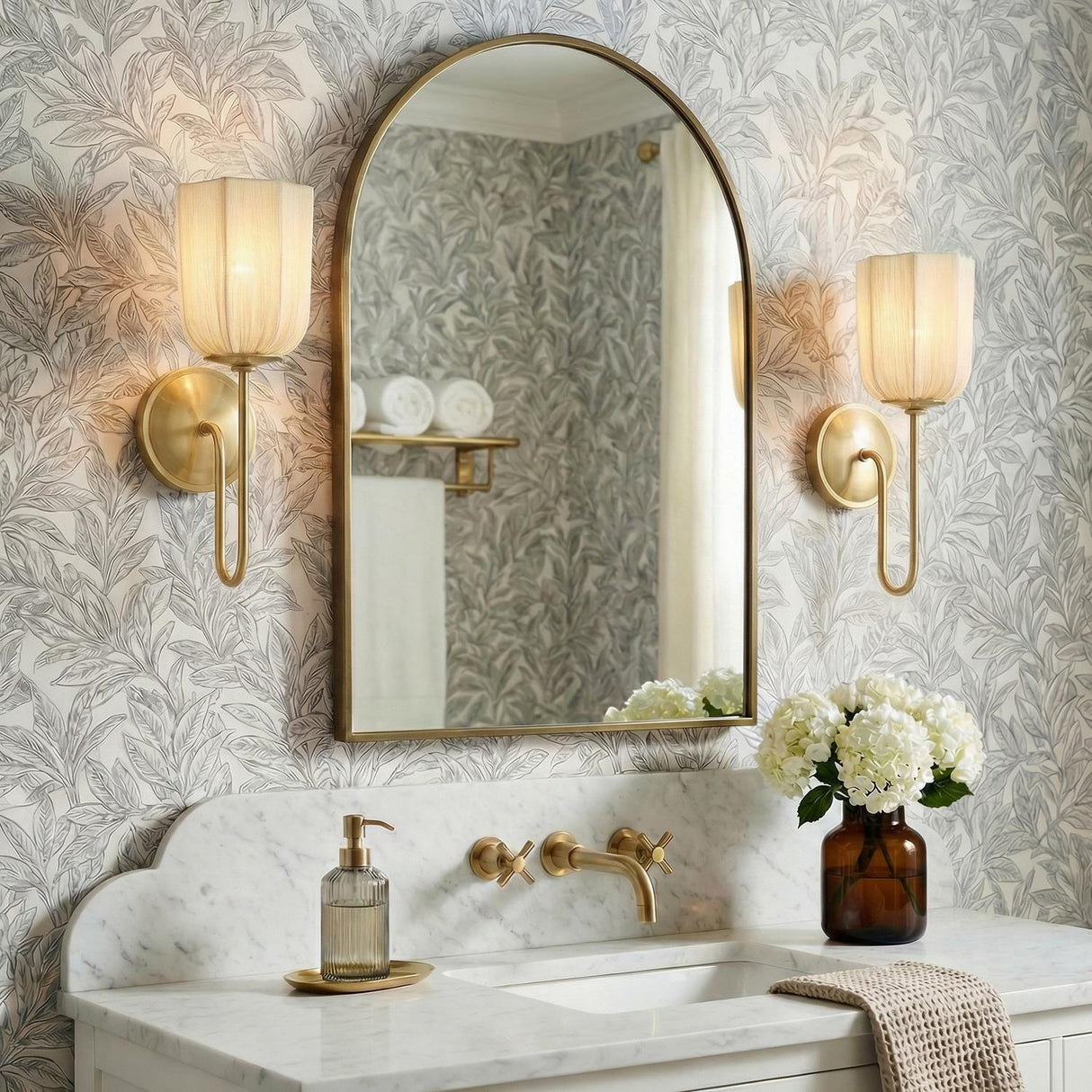 Lilith Aged Brass scalloped wall sconce in a Transitional Bathroom with an arched mirror and marble vanity.
