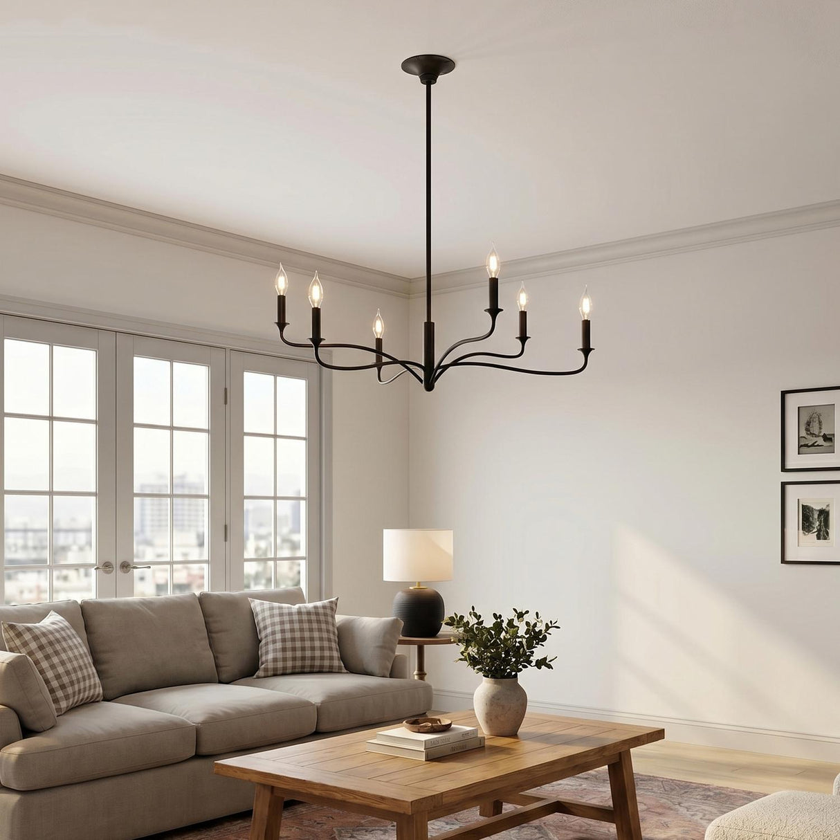 A transitional living room with the Harwick 6 Light Chandelier in an aged iron finish hanging above a beige sofa and white French doors.