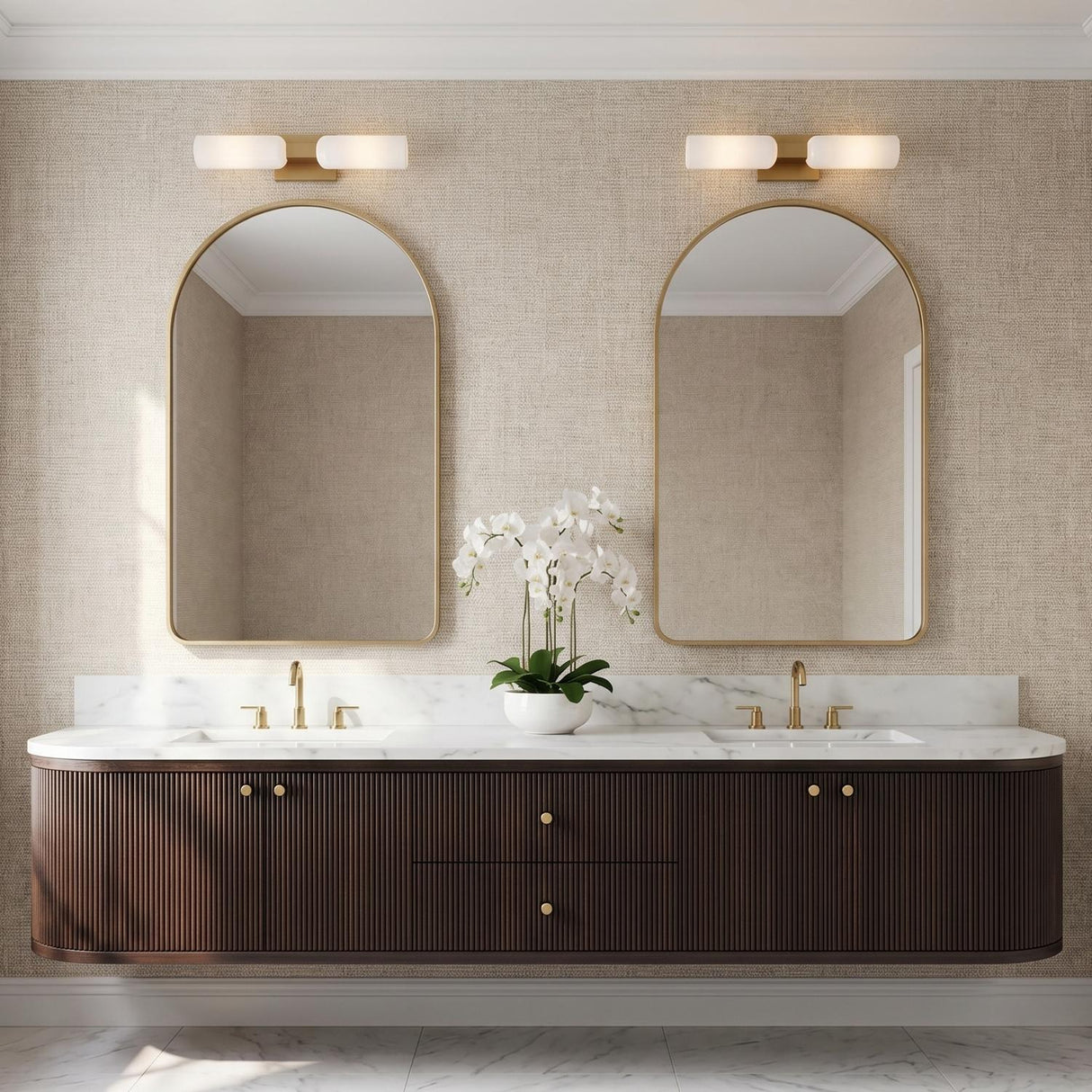 A contemporary bathroom with two modern brass vanity bars with frosted glass shades above gold arched mirrors and a fluted wood floating vanity with marble.