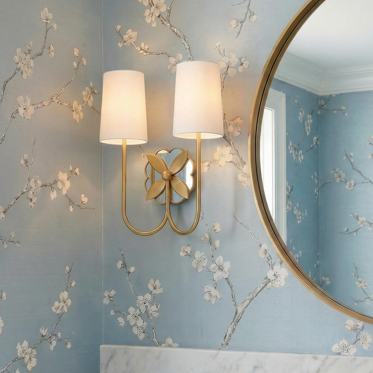 Ashby Brass and mirror glass leaf design wall sconce in a Traditional Bathroom with floral wallpaper and a gold mirror.