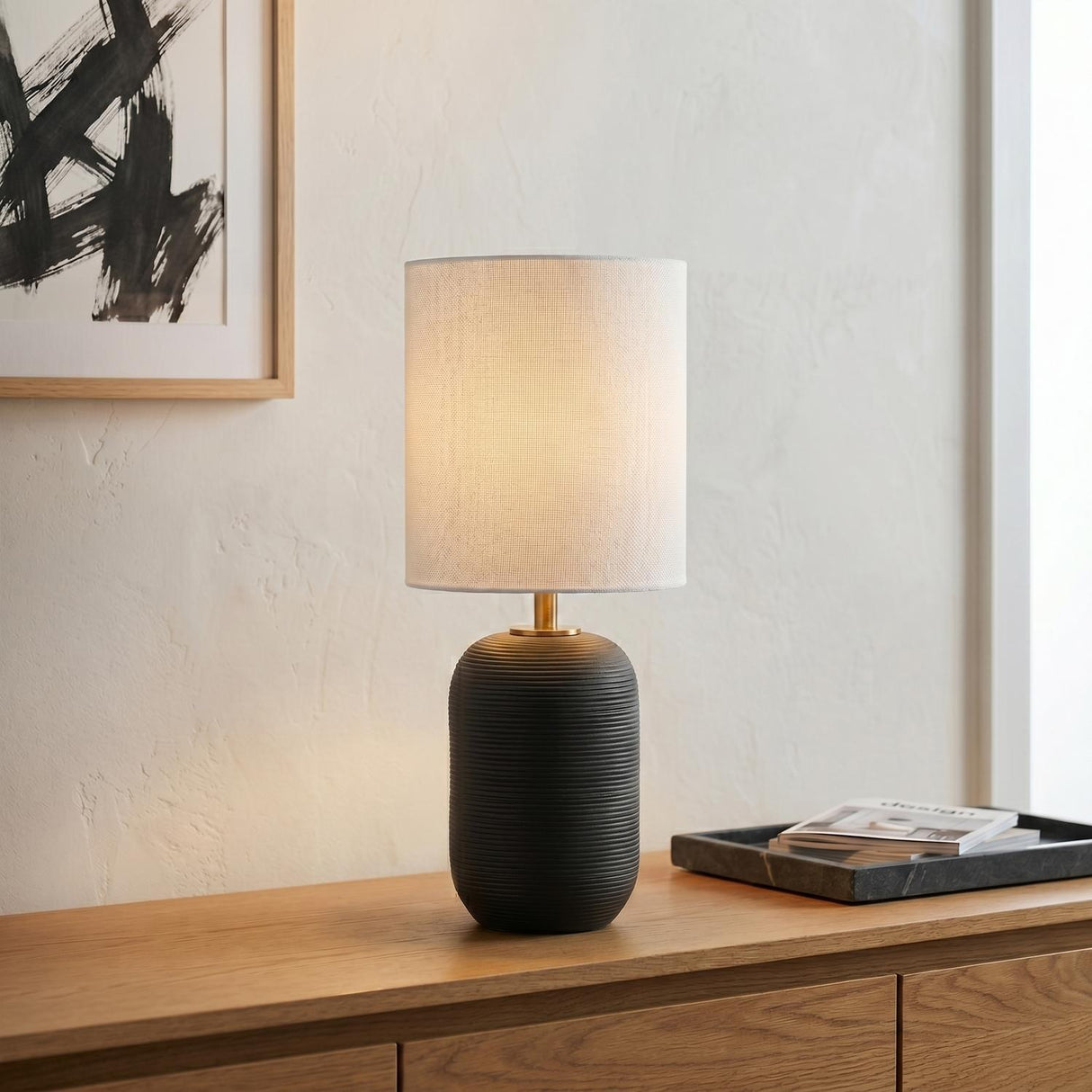 Nolette Small Table Lamp 14", Textured Black geometric Table Lamp in a Modern Living Room with an oak sideboard and abstract art.