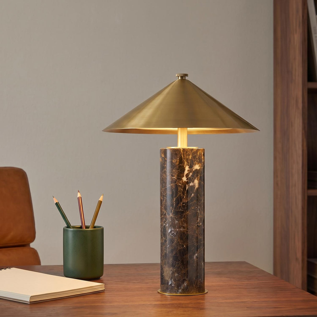 A mid-century office with the Gentry Rechargeable Table Lamp 15", Marble and Aged Brass featuring a cone shade on a walnut desk beside a leather chair.