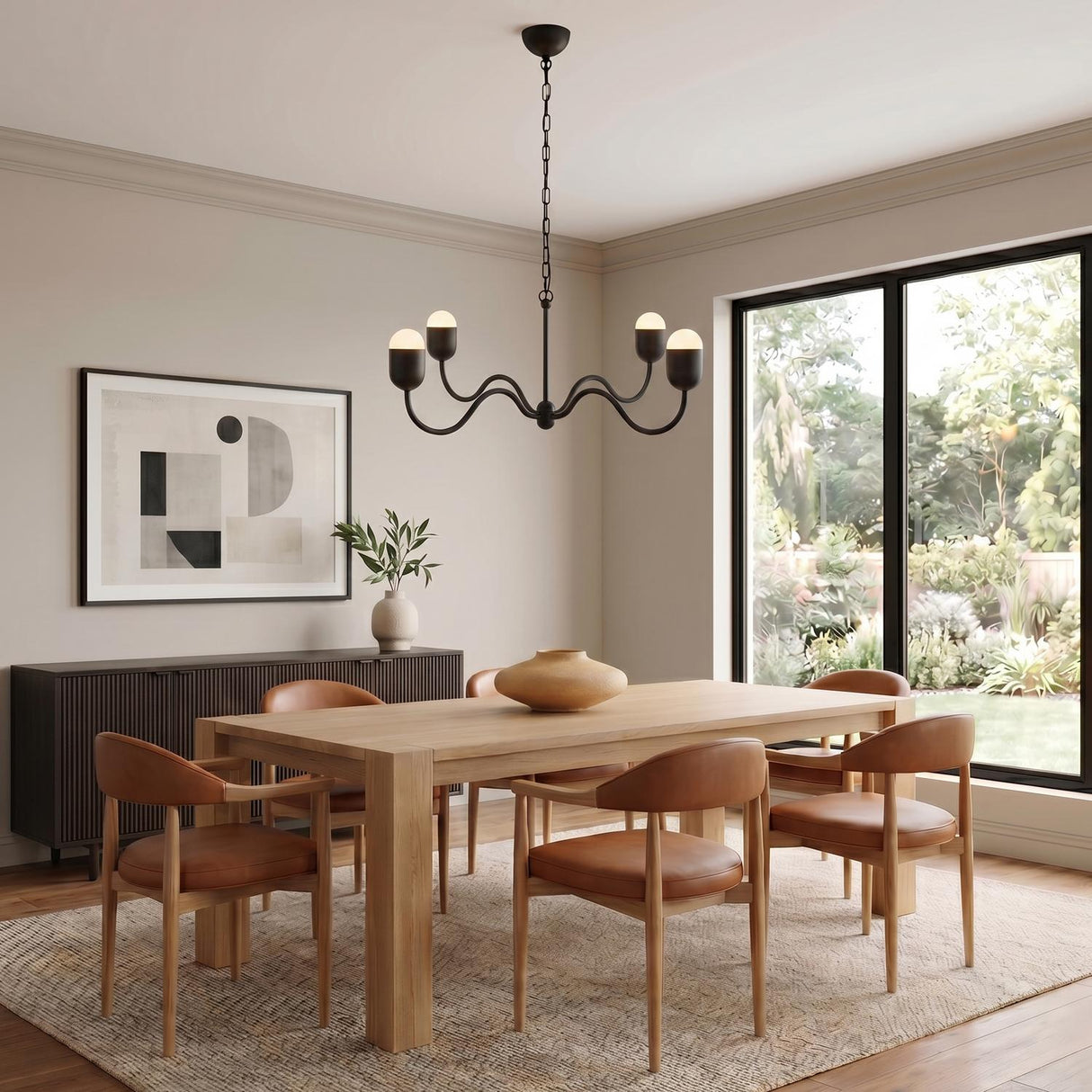 A contemporary dining room with the Rubina 4 Light Chandelier in matte black centered over a light wood dining table and cognac leather chairs.