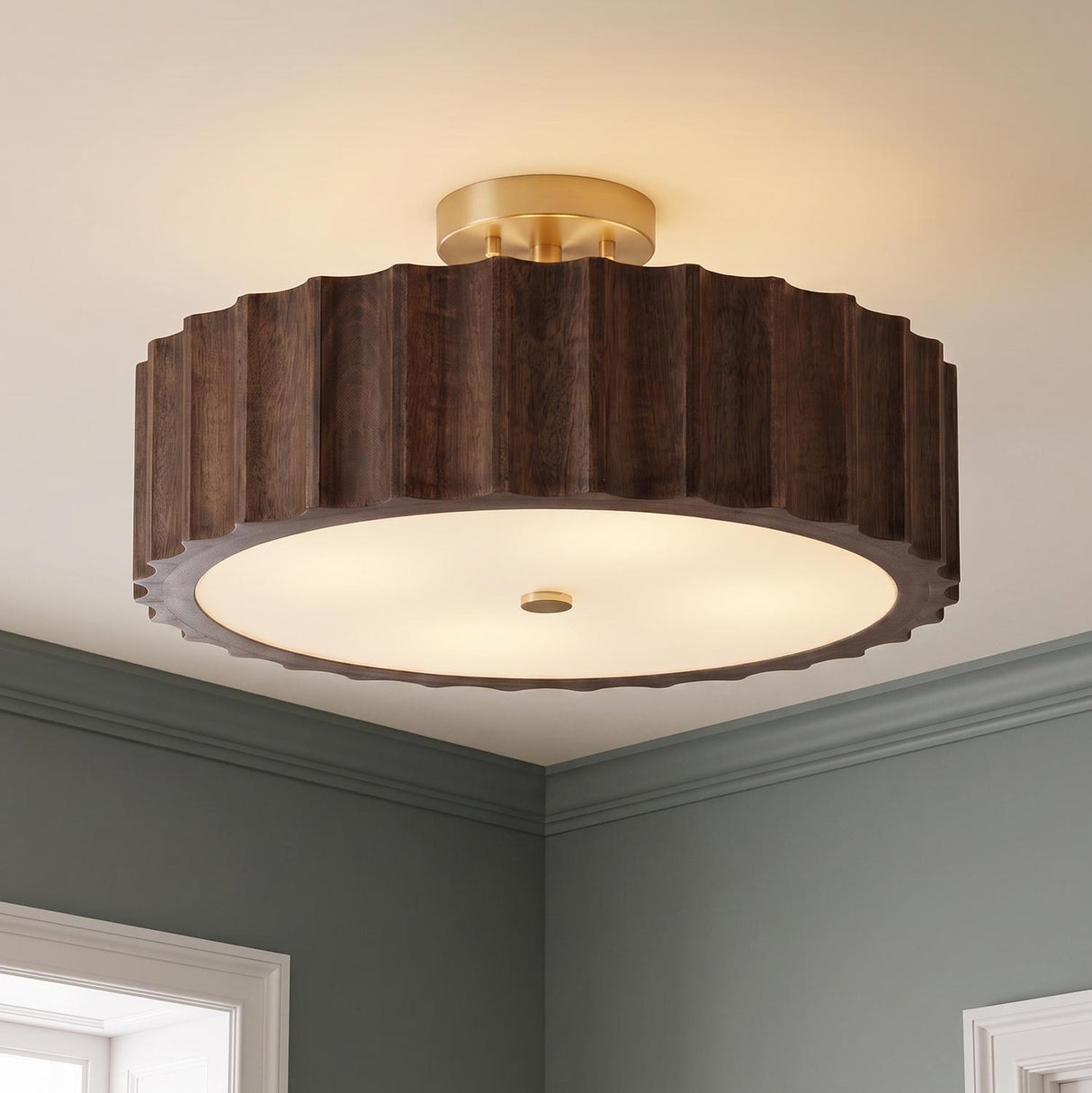 A transitional foyer with a matte brass and espresso wood semi-flush mount installed along the ceiling center between grey walls and white decorative door trim.