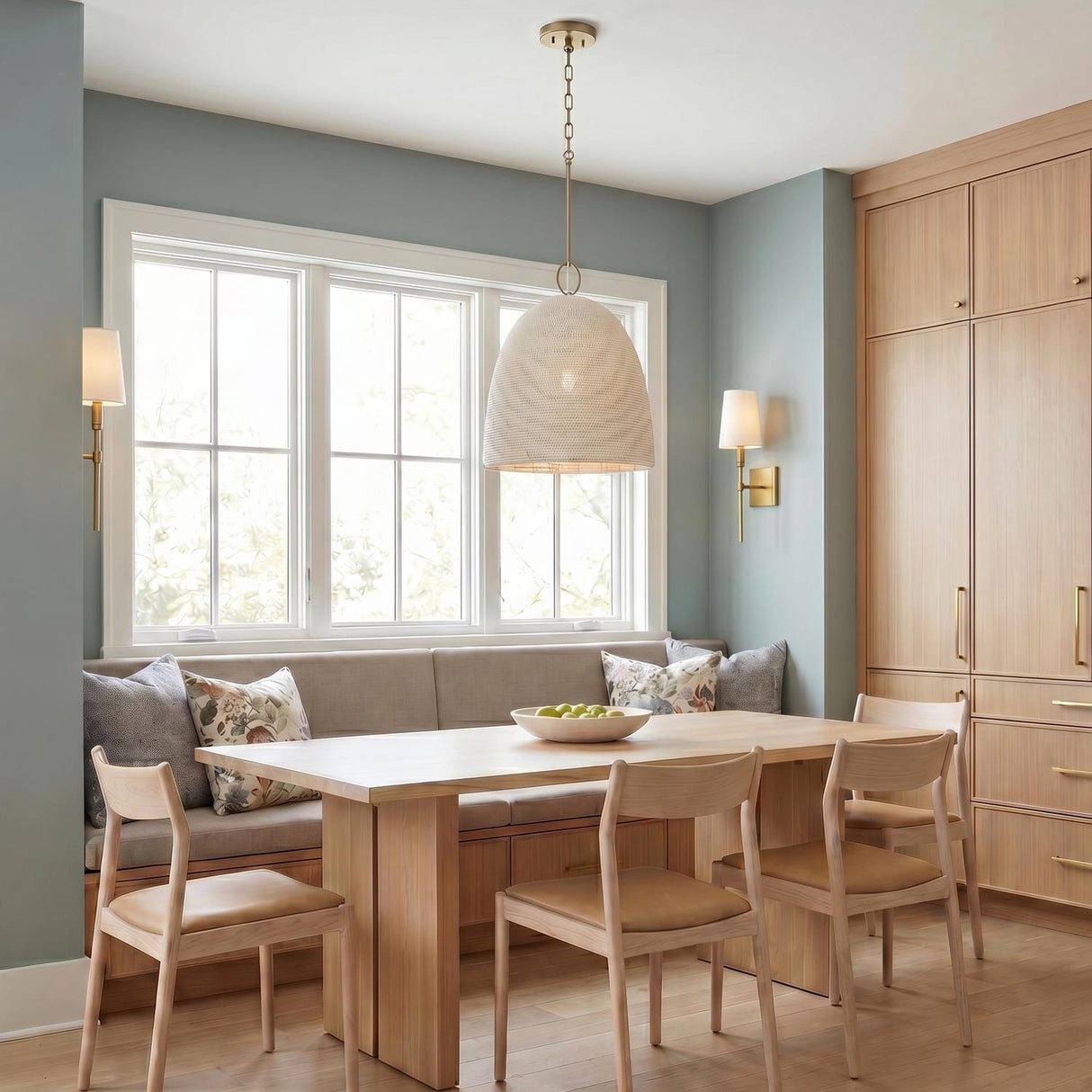 A transitional dining room with an aged brass and ivory beaded pendant over a light wood table with matching wall sconces and built-in wood cabinets.