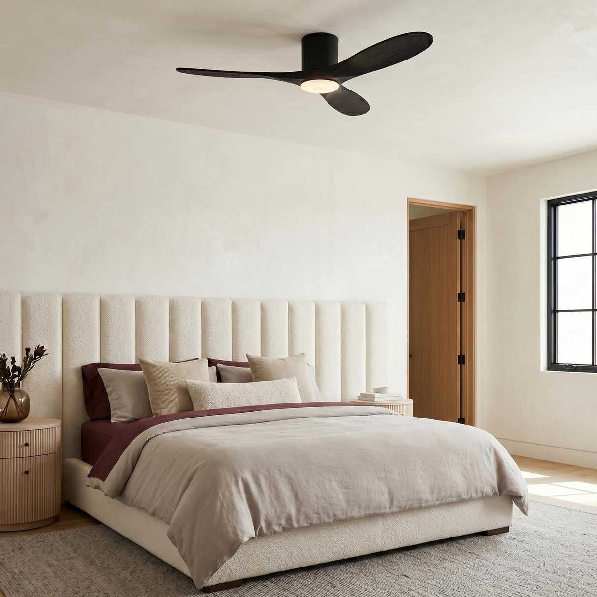 A modern bedroom featuring the Eider LED Ceiling Fan 52", Matte Black Oak at the ceiling center above a cream channeled headboard and light oak nightstands.