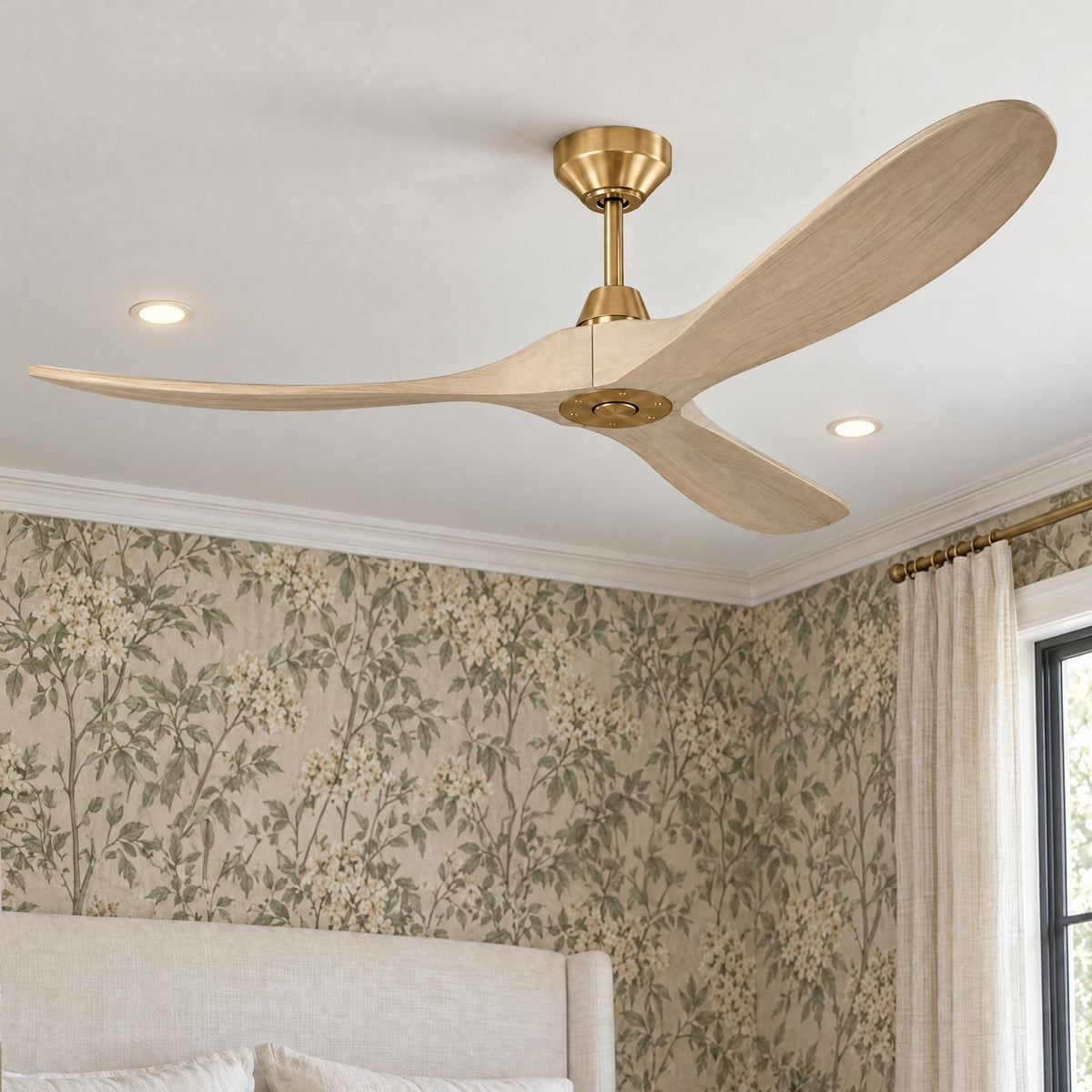 A transitional bedroom featuring the Egret Ceiling Fan 60", Whitewash Oak and Modern Brass centered on a ceiling above a linen headboard and floral wallpaper.