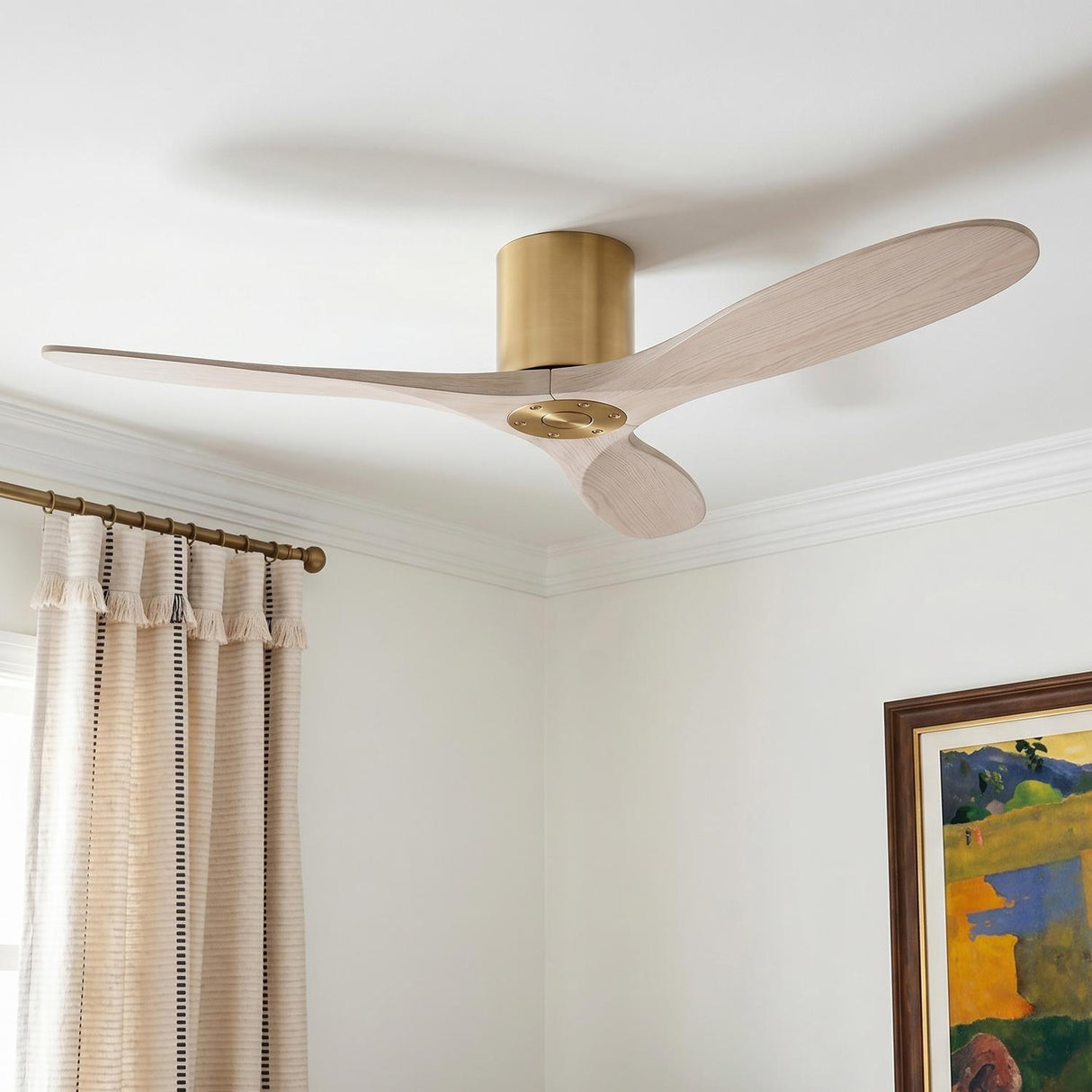 A contemporary living room with the Eider Ceiling Fan 52" in matte white oak and modern brass mounted on a standard ceiling beside striped curtains.