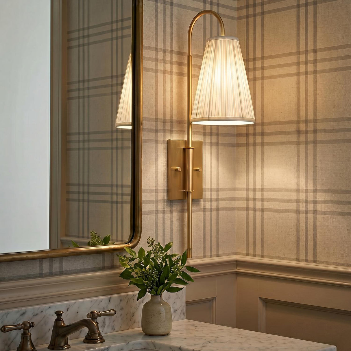 A traditional bathroom with the Wynn Wall Sconce 24", Vintage Brass featuring a white pleated linen shade mounted beside a brass-framed mirror and marble vanity.