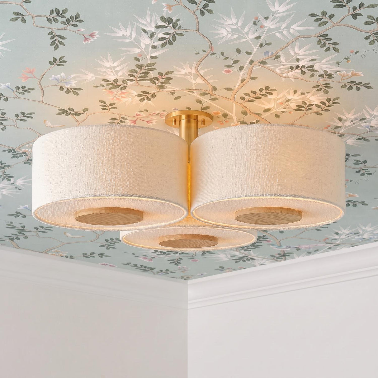 A transitional bedroom with the Wolfe Extra Large Semi-Flush in ivory boucle and aged brass on the ceiling center, featuring floral chinoiserie wallpaper and white crown molding.