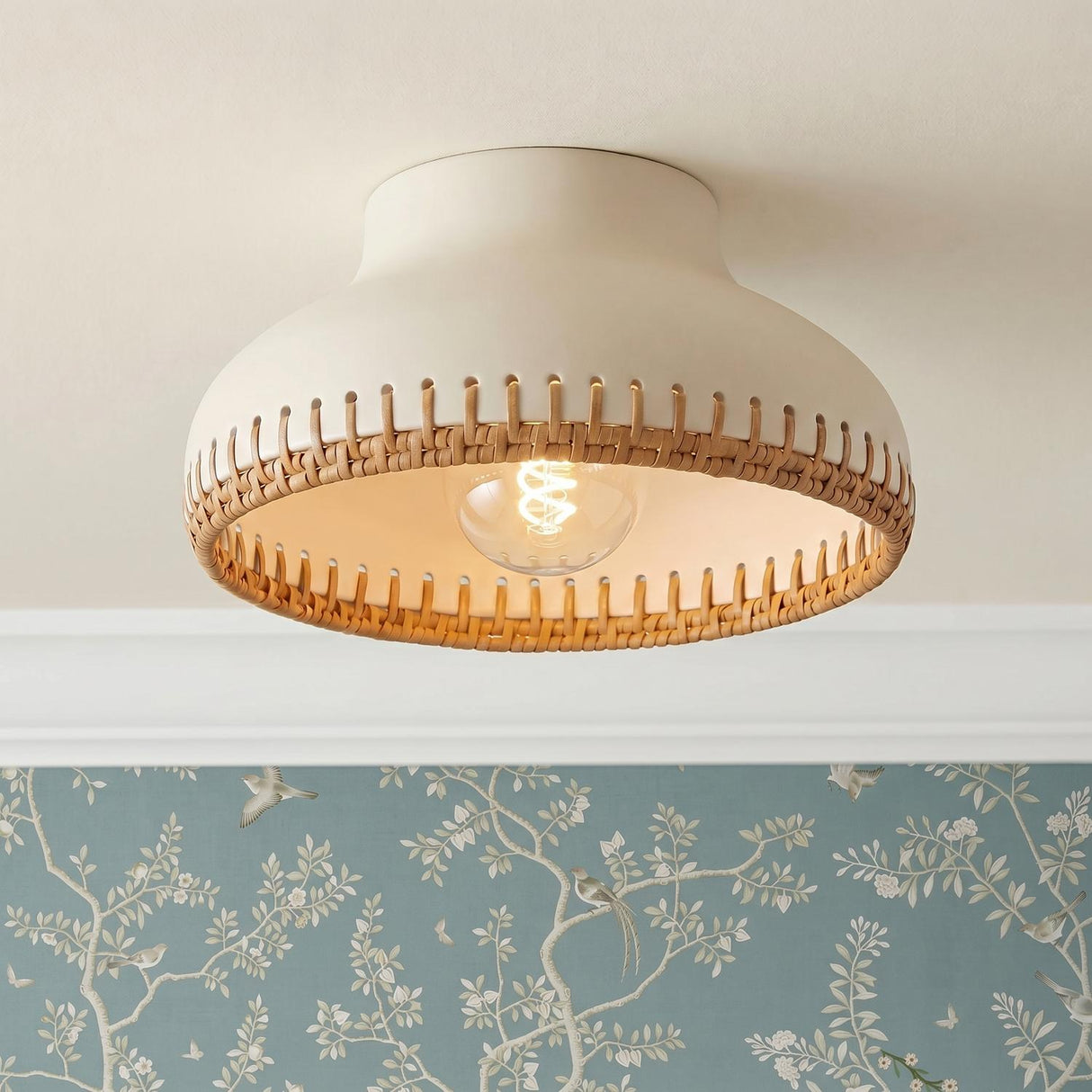 A cottage bedroom featuring the Nadira Semi-Flush 11 inch Cream and Rattan light on a white ceiling above blue floral bird-patterned wallpaper and white crown molding.