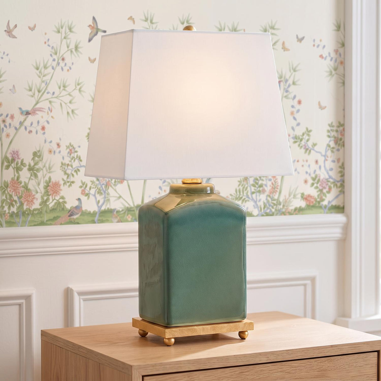 A traditional living room featuring the Hallie Table Lamp 17 inch Jade Glaze with White Shade on a natural wood side table against floral bird wallpaper.