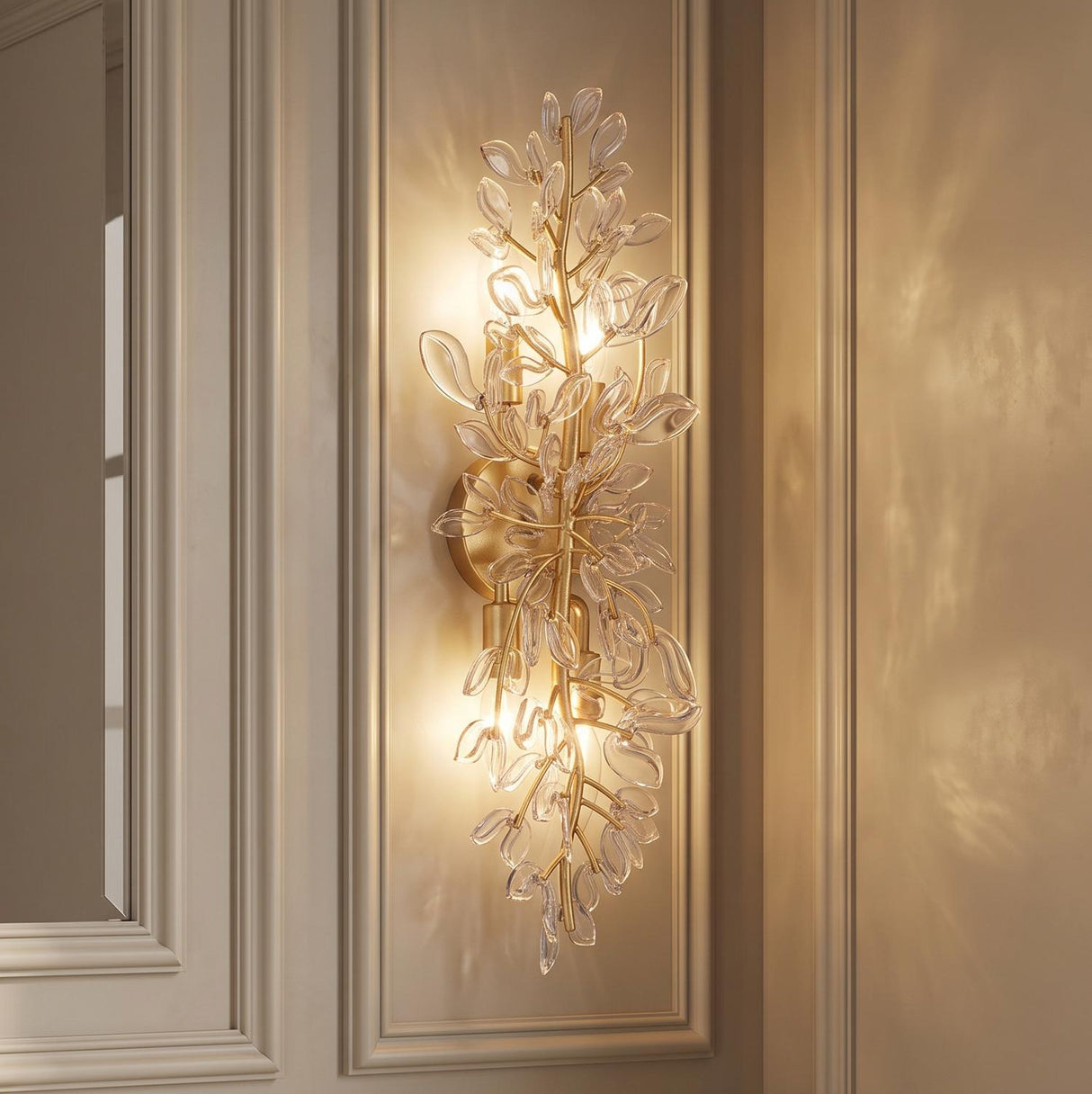 A transitional hallway with an Esme Wall Sconce 24", Soft Brass and Clear Glass featuring leaf accents mounted on a beige paneled wall.