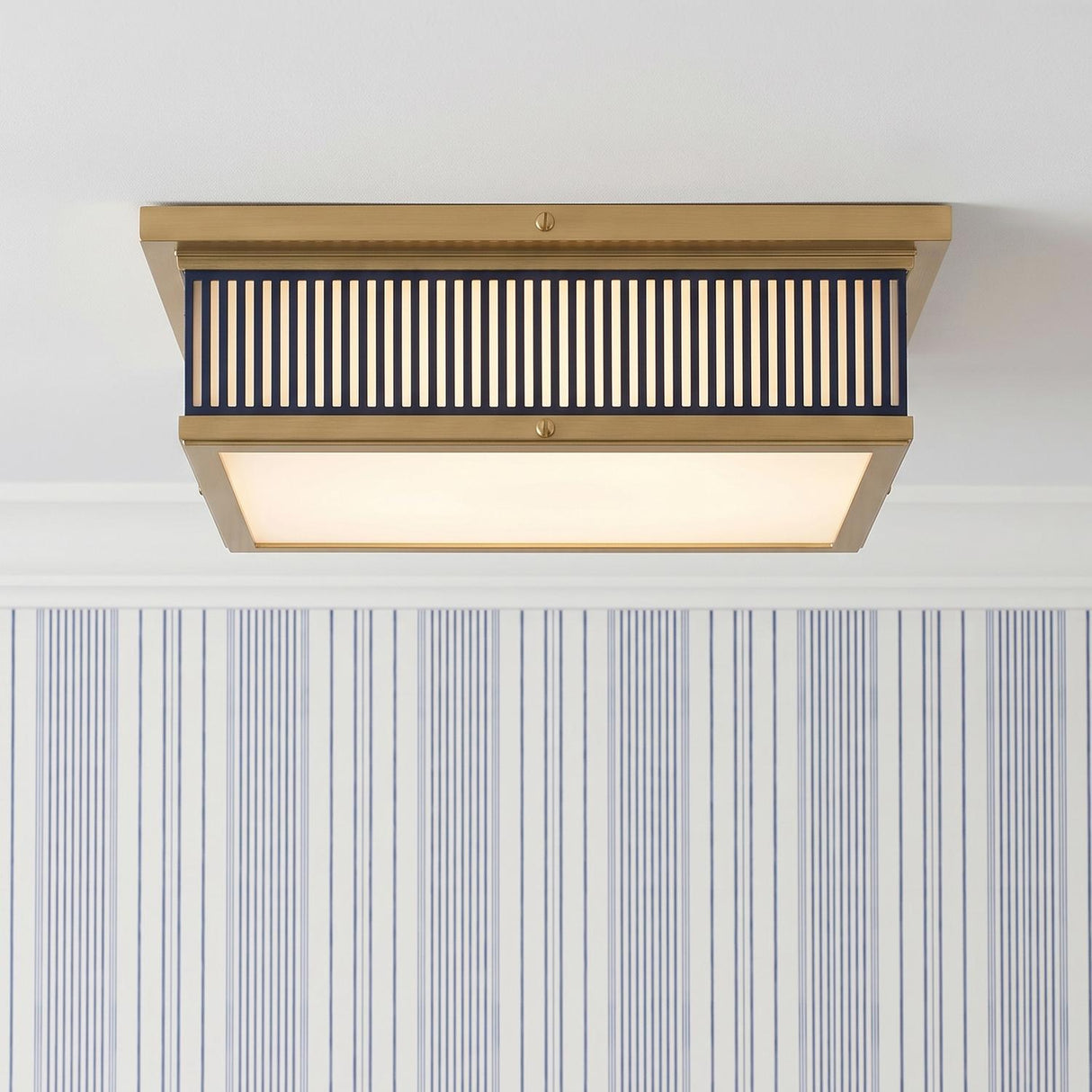A transitional foyer with the Hawthorne Square LED Flush Mount in aged brass and midnight blue along the ceiling with blue pinstripe wallpaper and white crown molding.